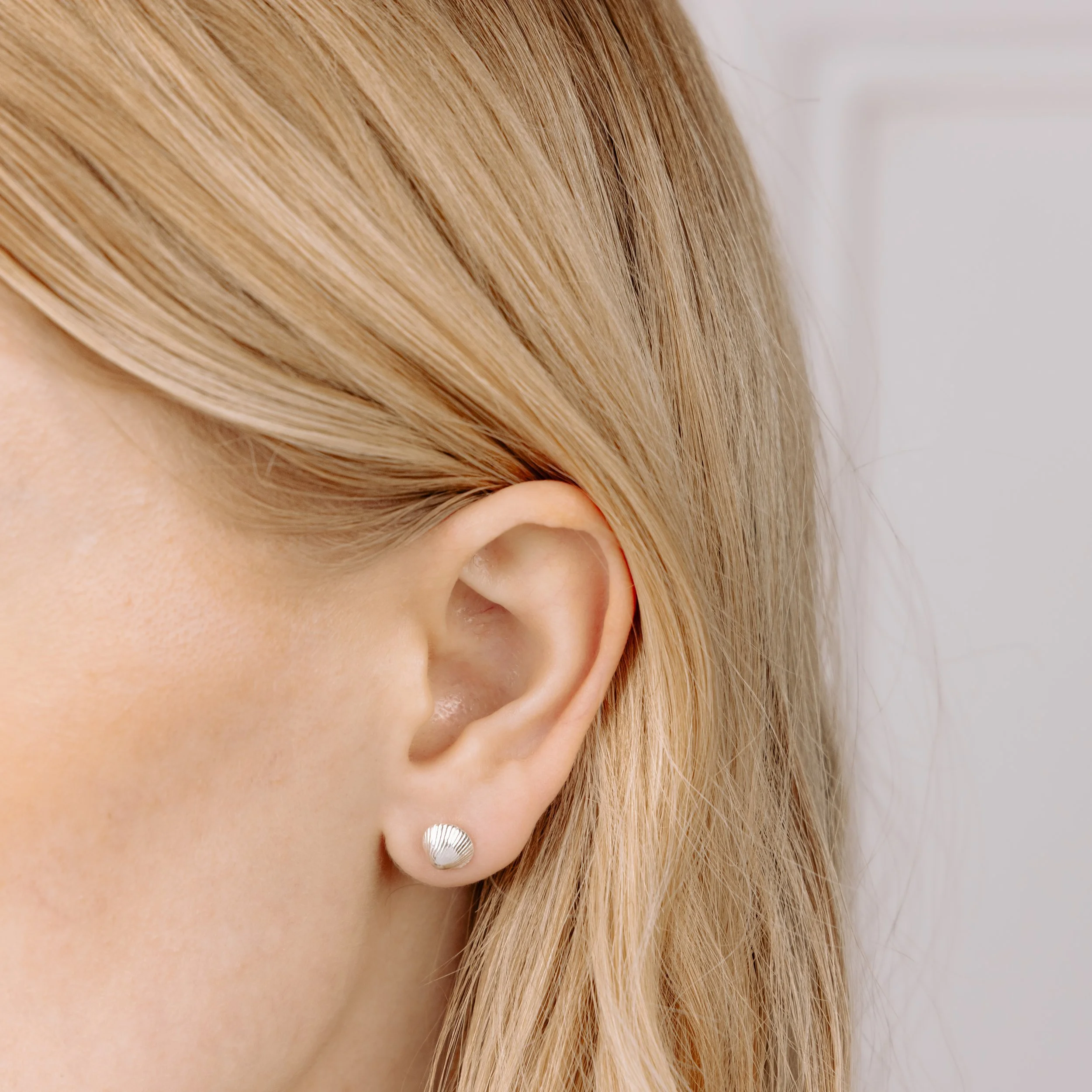 Sterling silver clamshell stud earrings with textured detailing, inspired by coastal seashells.