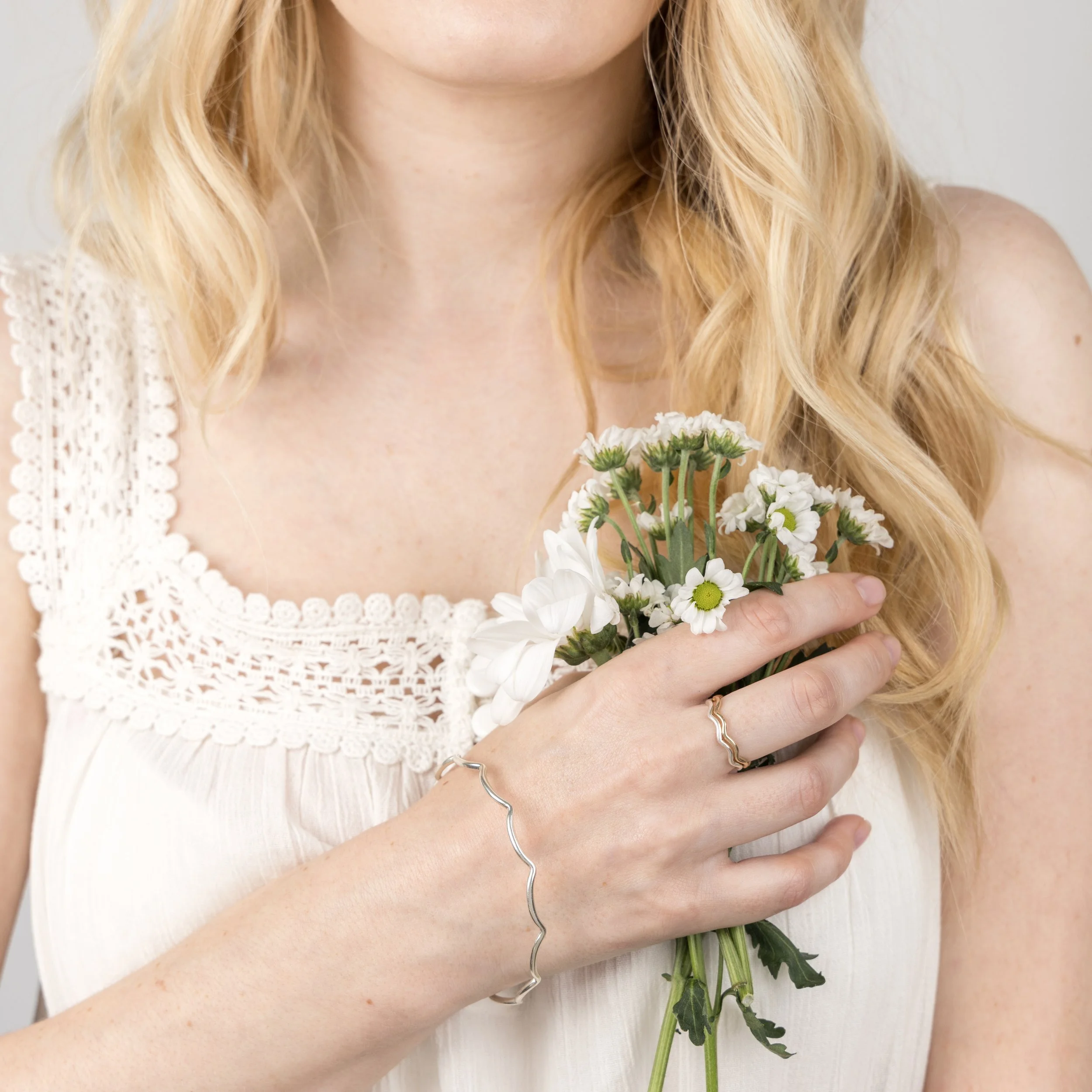 Slim sterling silver stacking bangle with a polished wave design, perfect for layering in a modern minimalist style or simply worn alone.