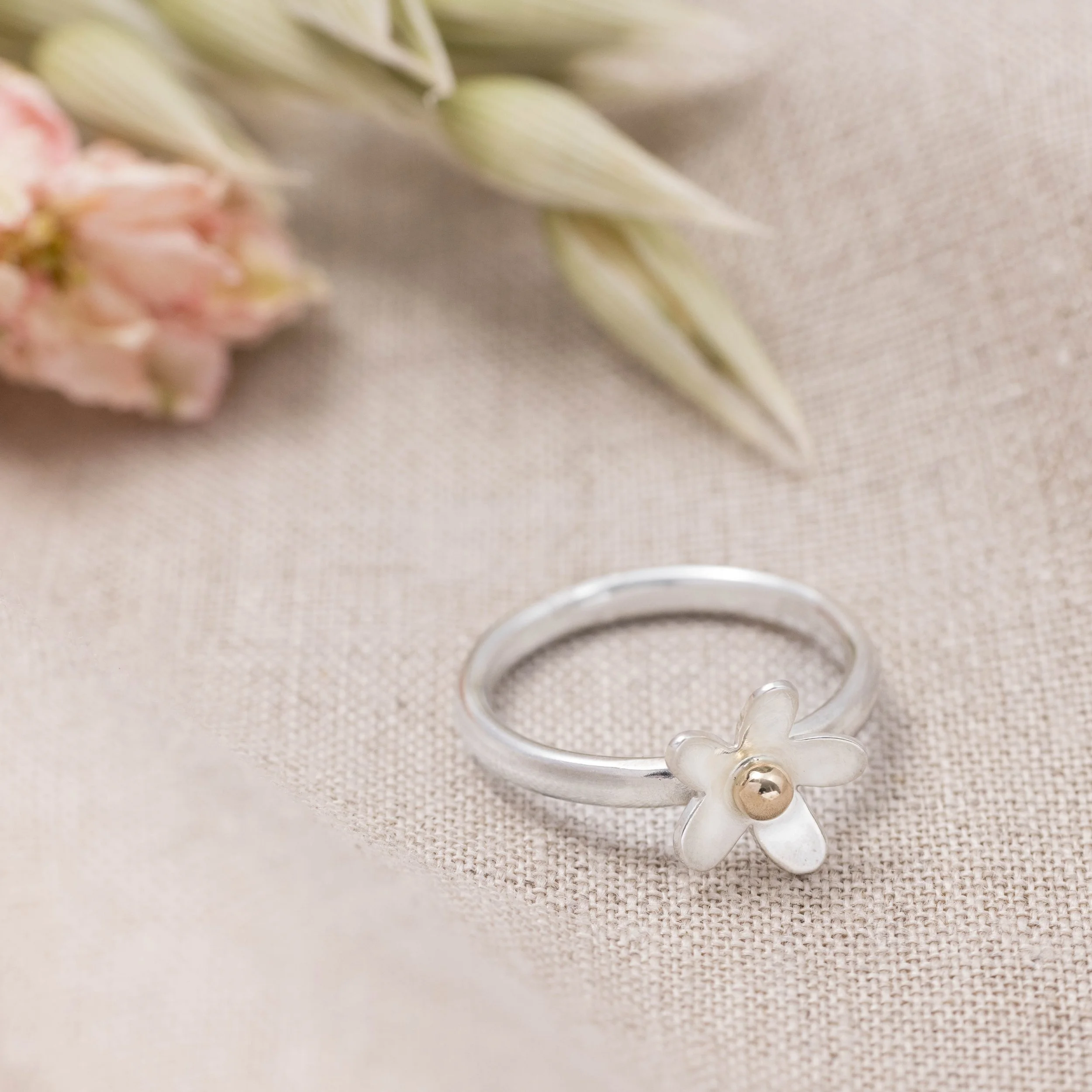Sterling silver daisy ring with a polished band and detailed medium-sized flower design featuring 9ct gold stamen and a domed centre.