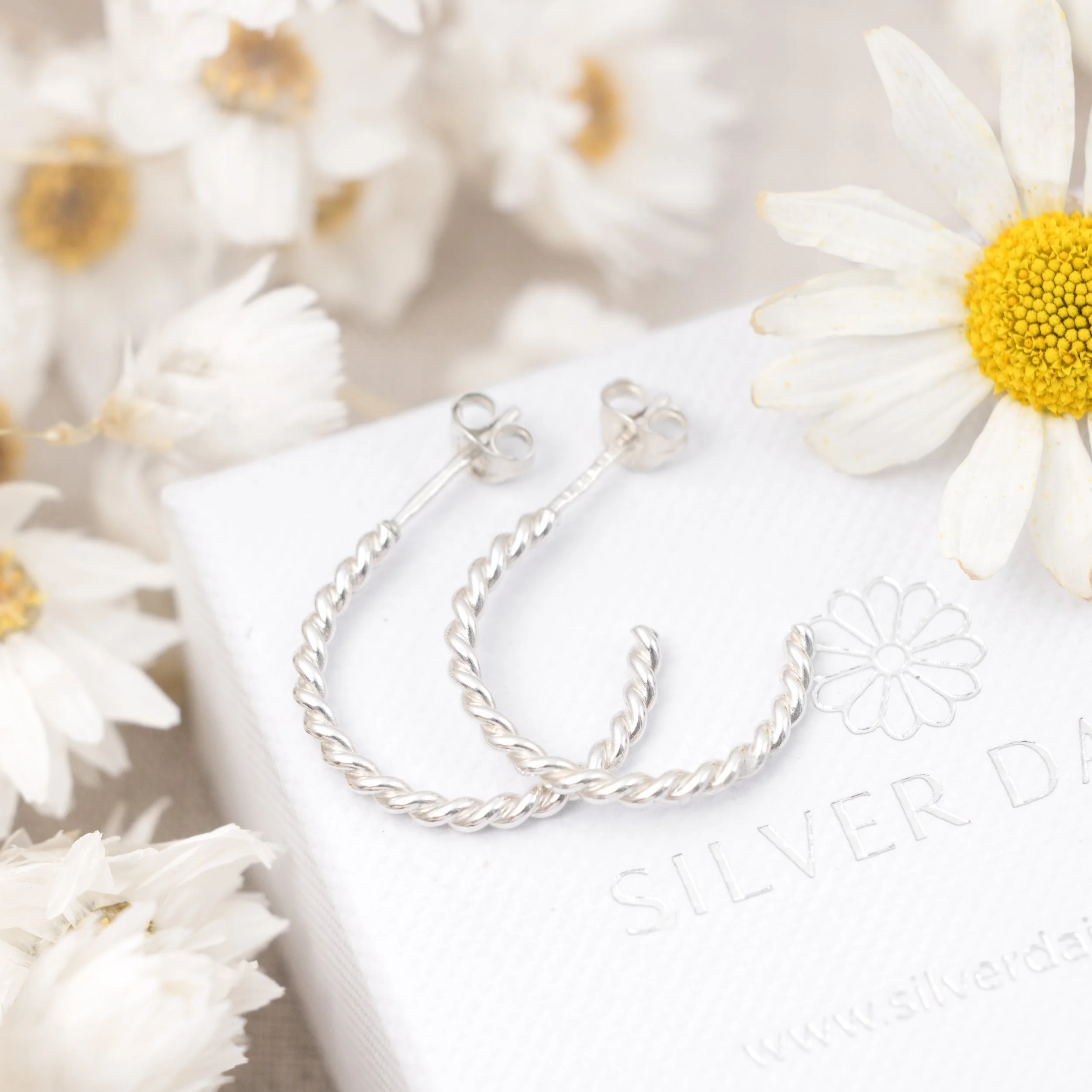 Polished sterling silver twist hoop earrings with a textured spiral design, lightweight and elegant for everyday wear.