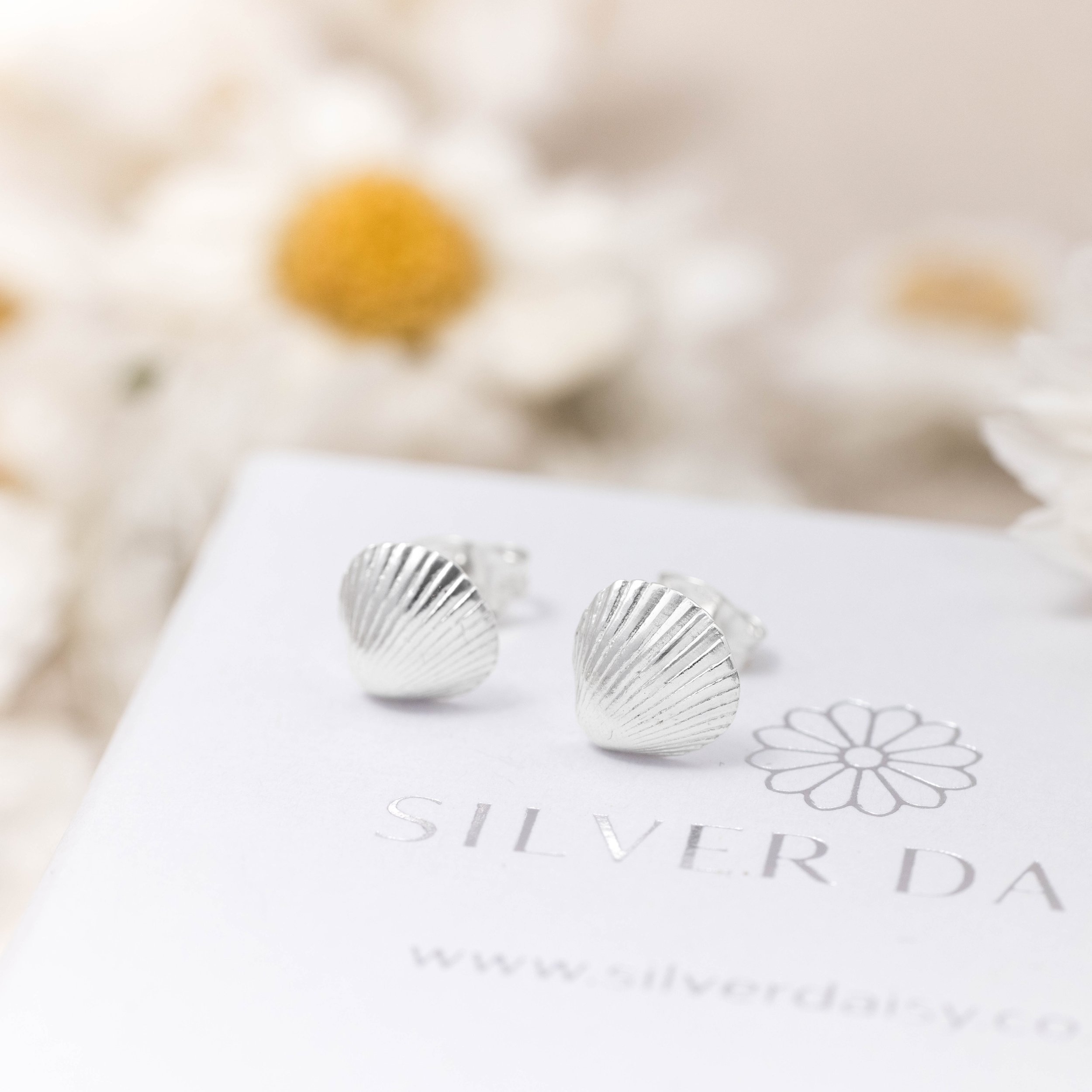 Sterling silver clamshell stud earrings with textured detailing, inspired by coastal seashells.