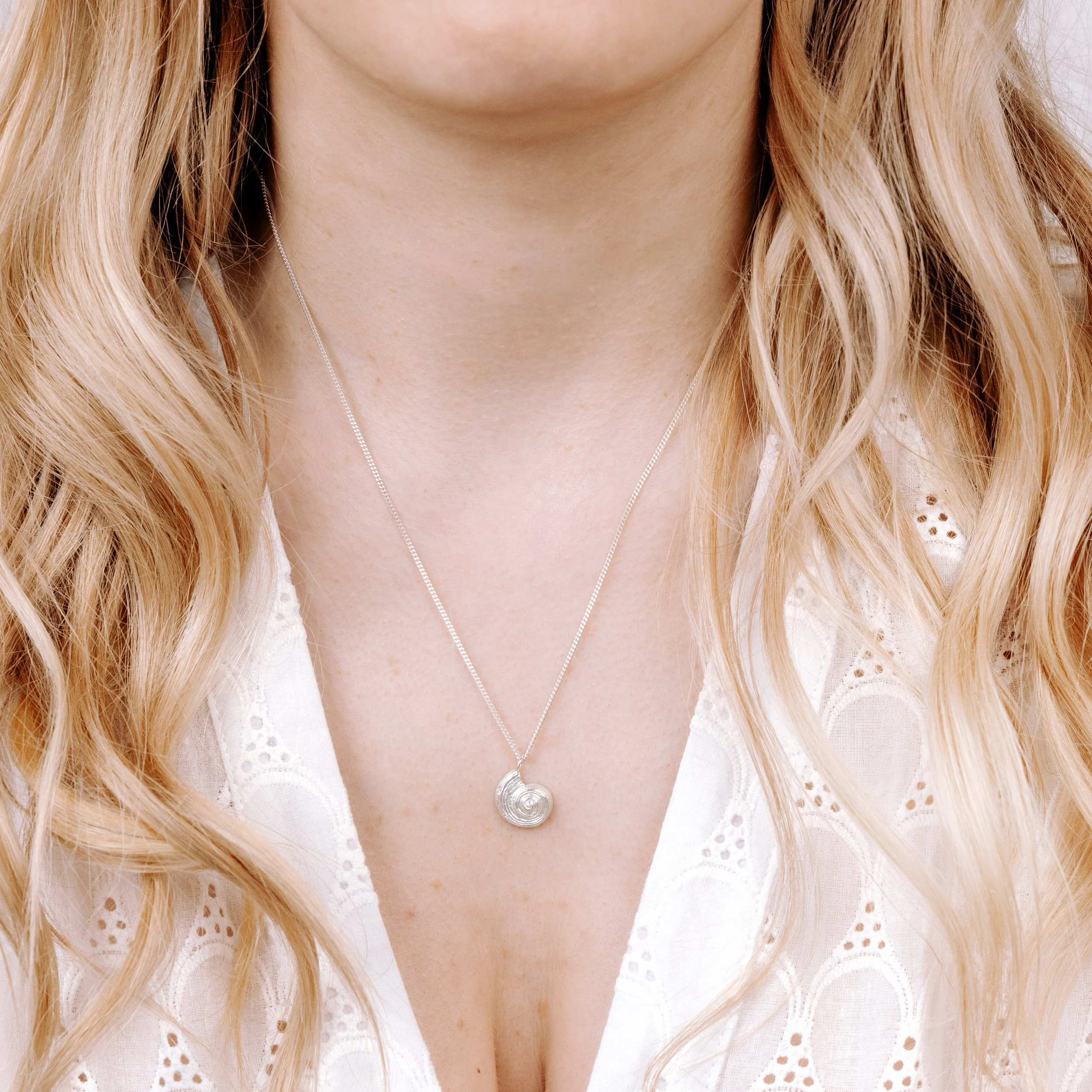 Sterling silver pendant necklace with a detailed fossil ammonite design on a fine chain, inspired by coastal and seaside jewellery.