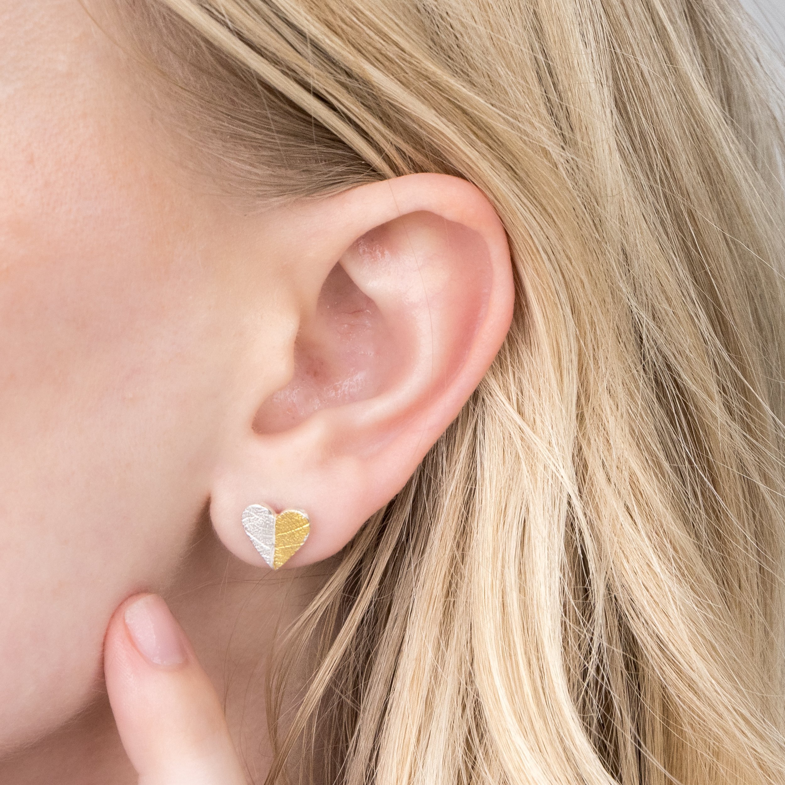 Sterling silver heart-shaped stud earrings with textured leaf pattern and gold keum-boo accents.