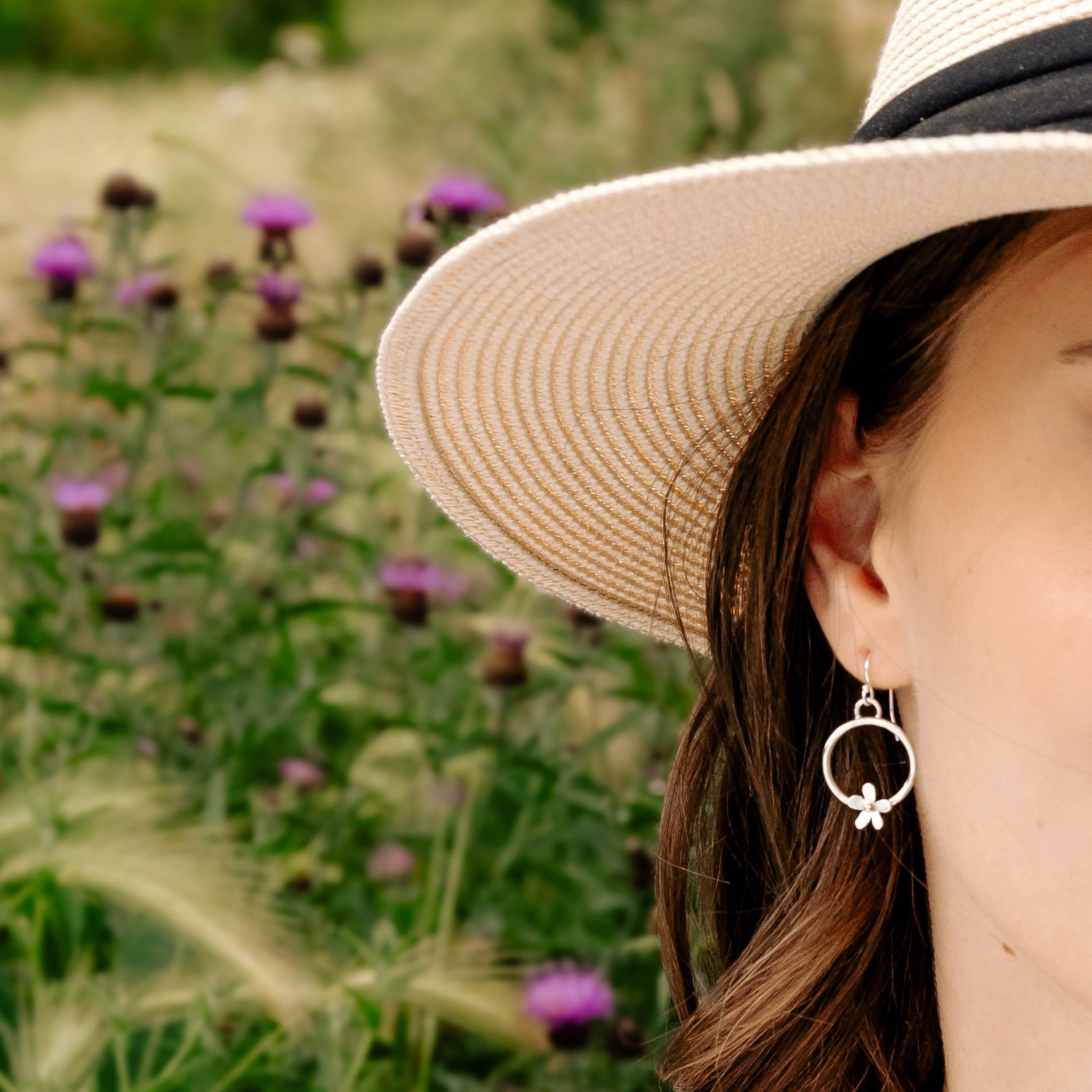 Sterling silver hoop earrings with delicate daisy flower charms, featuring 9ct gold stamen, and a polished and lightweight finish.