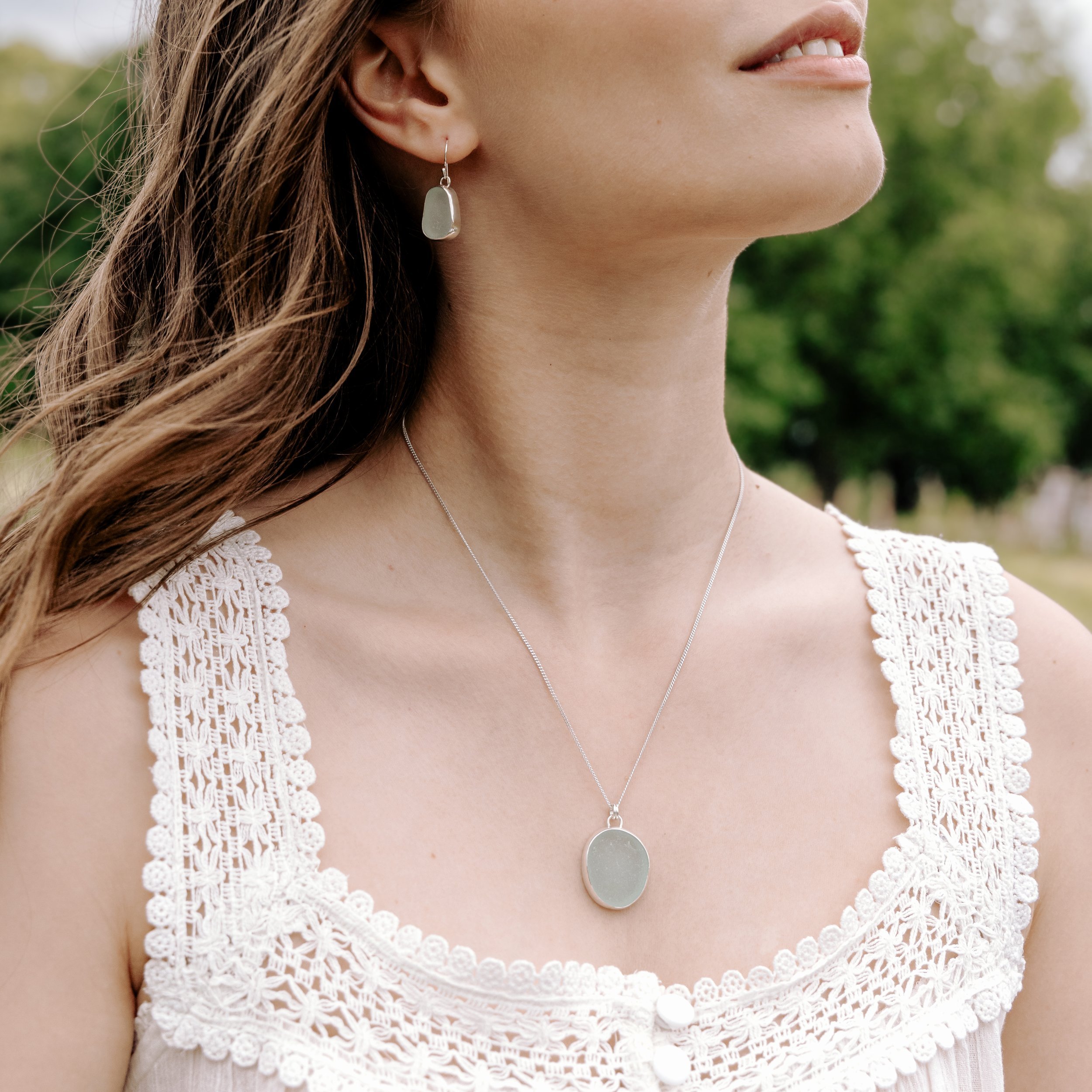 Aqua sea glass pebble set in polished silver on a delicate chain, coastal-inspired handmade necklace.