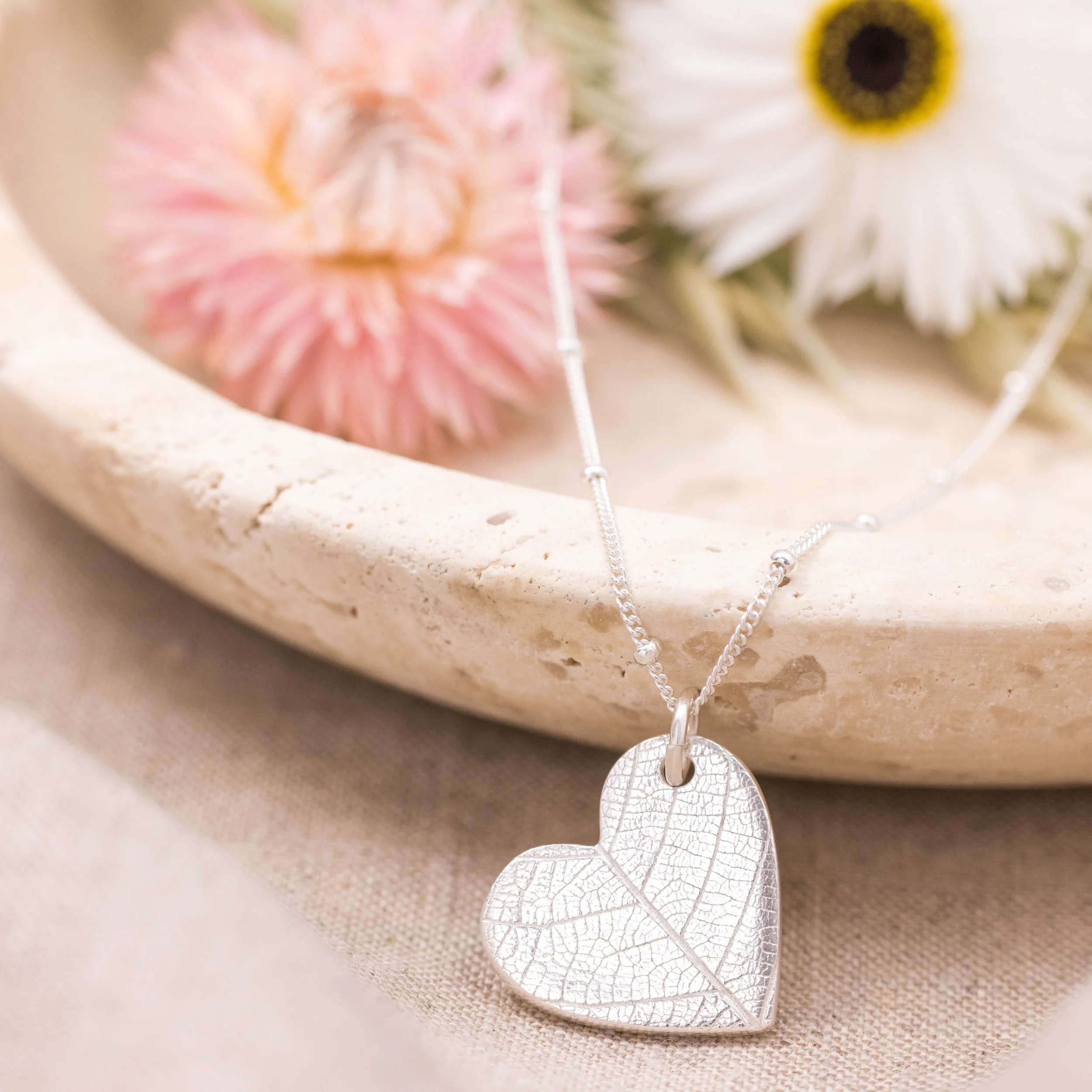 Sterling silver heart pendant with delicate leaf vein texture on a fine silver chain.