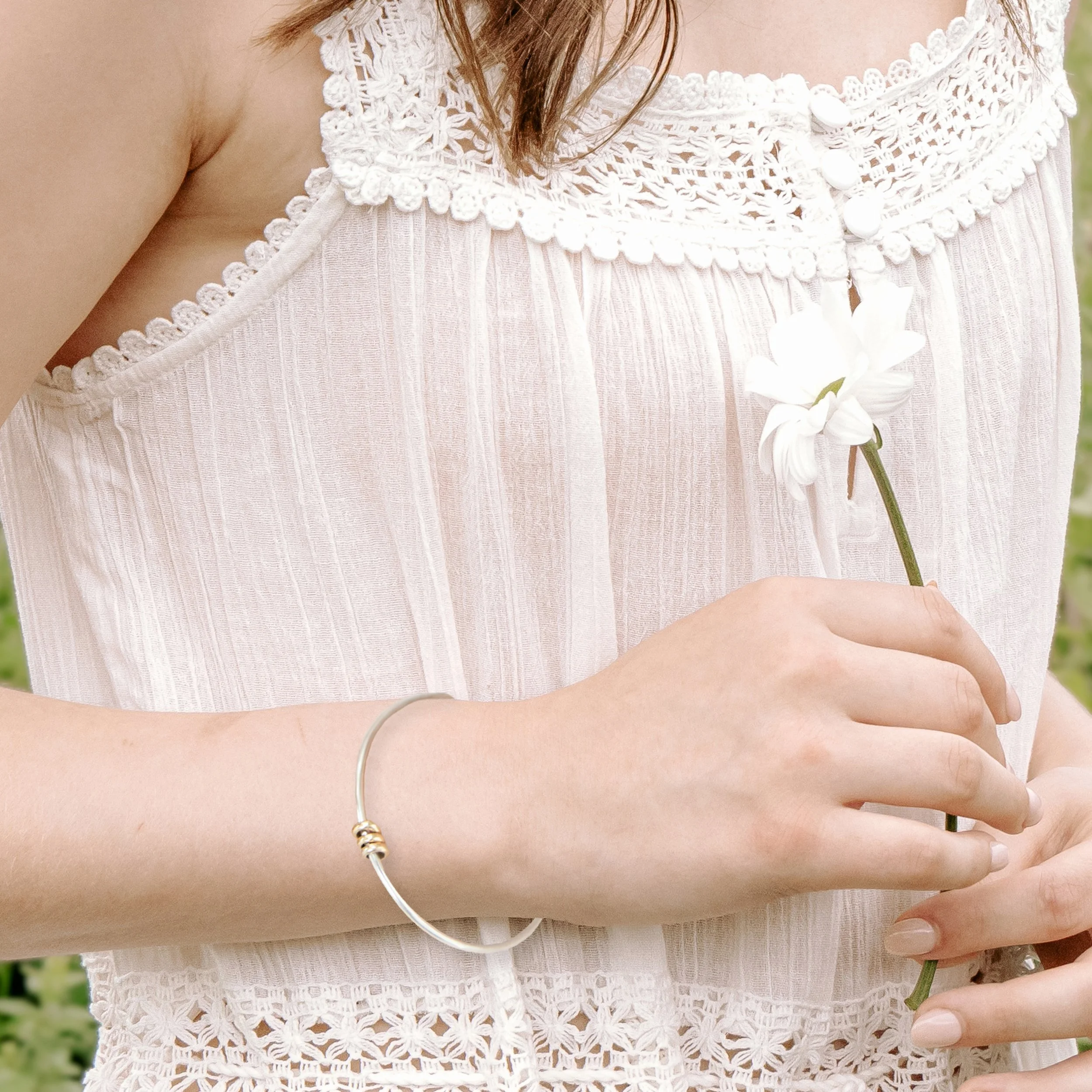 Sterling silver bangle with polished 9ct gold satellite rings which move freely around the band. An elegant fidget bracelet.