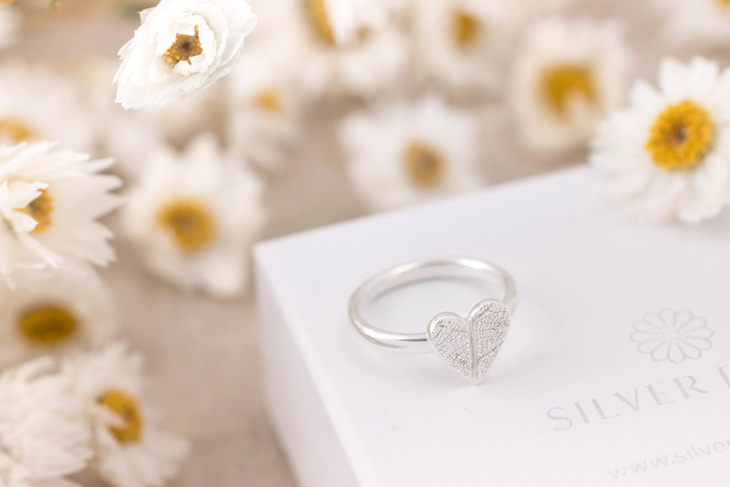 Sterling silver heart-shaped ring with delicate pressed leaf pattern on a polished band.
