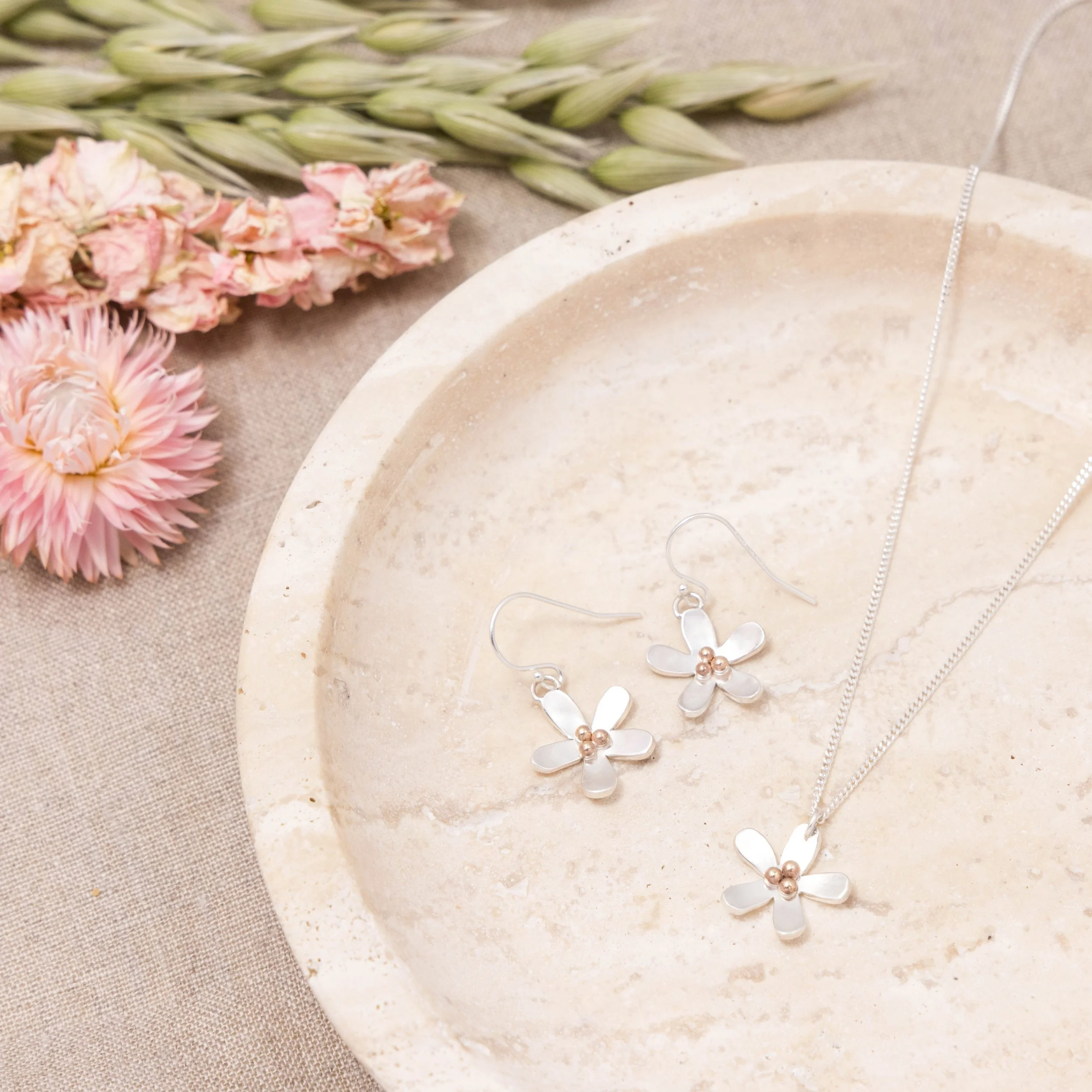 Sterling silver daisy pendant necklace with polished petals and a 9ct gold stamen on a delicate silver chain.