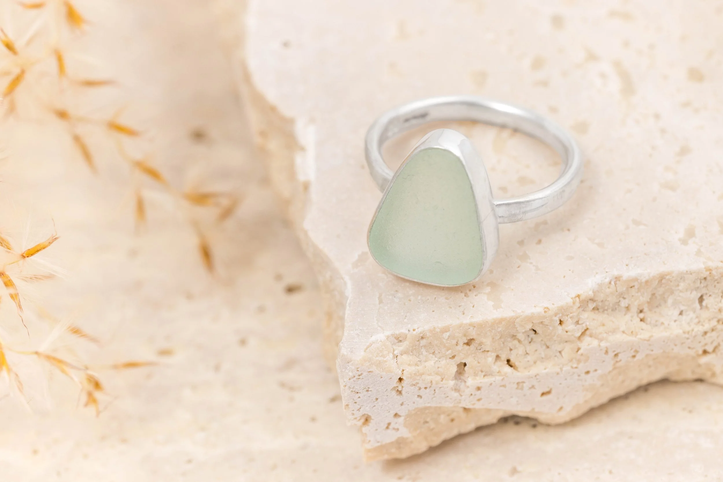 Sterling silver ring with a smooth aquamarine sea glass gemstone in a polished bezel setting on a slim oval band. Coastal beach inspired jewellery.
