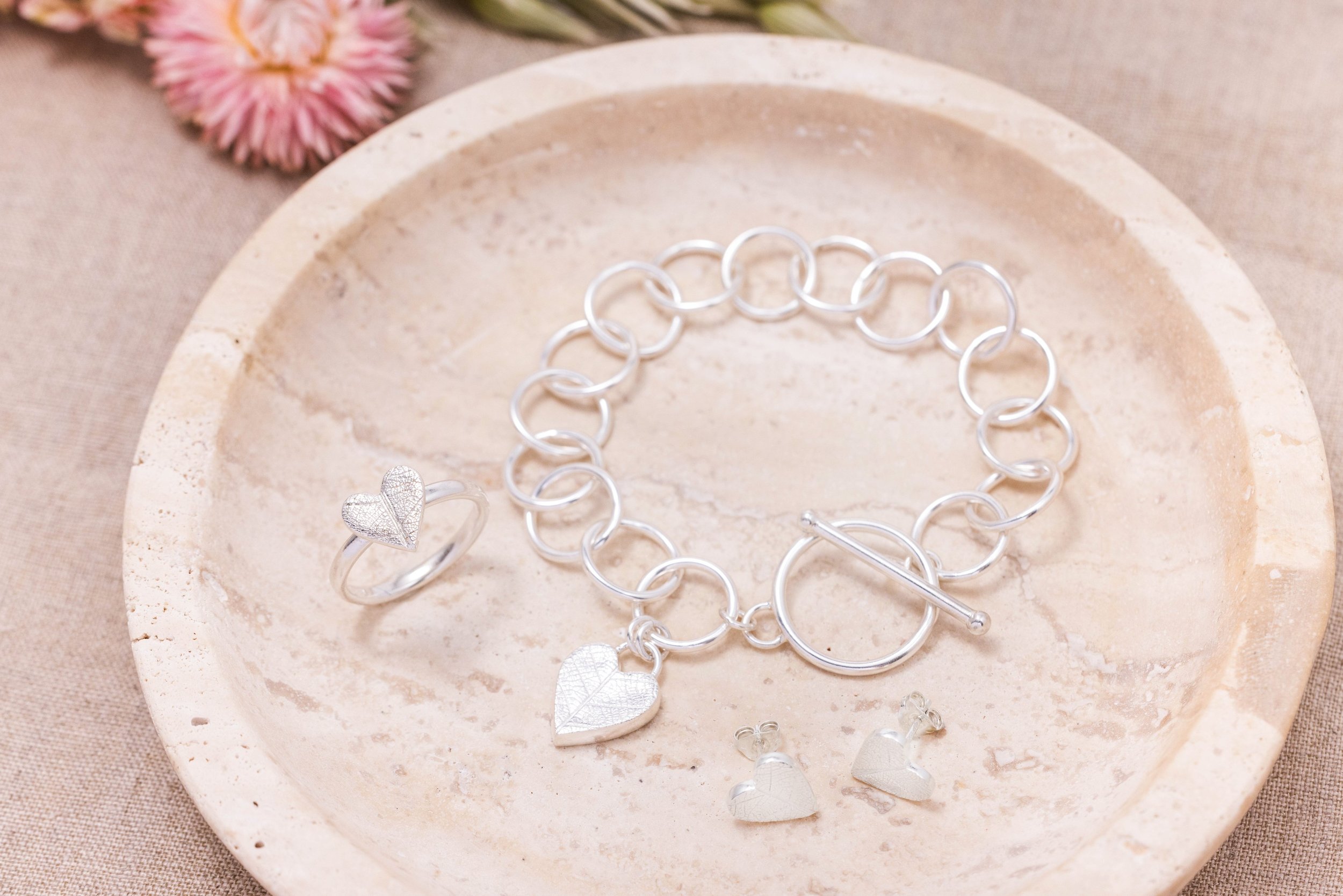 Sterling silver bracelet with a textured heart charm featuring a delicate leaf pattern, finished with a toggle clasp.