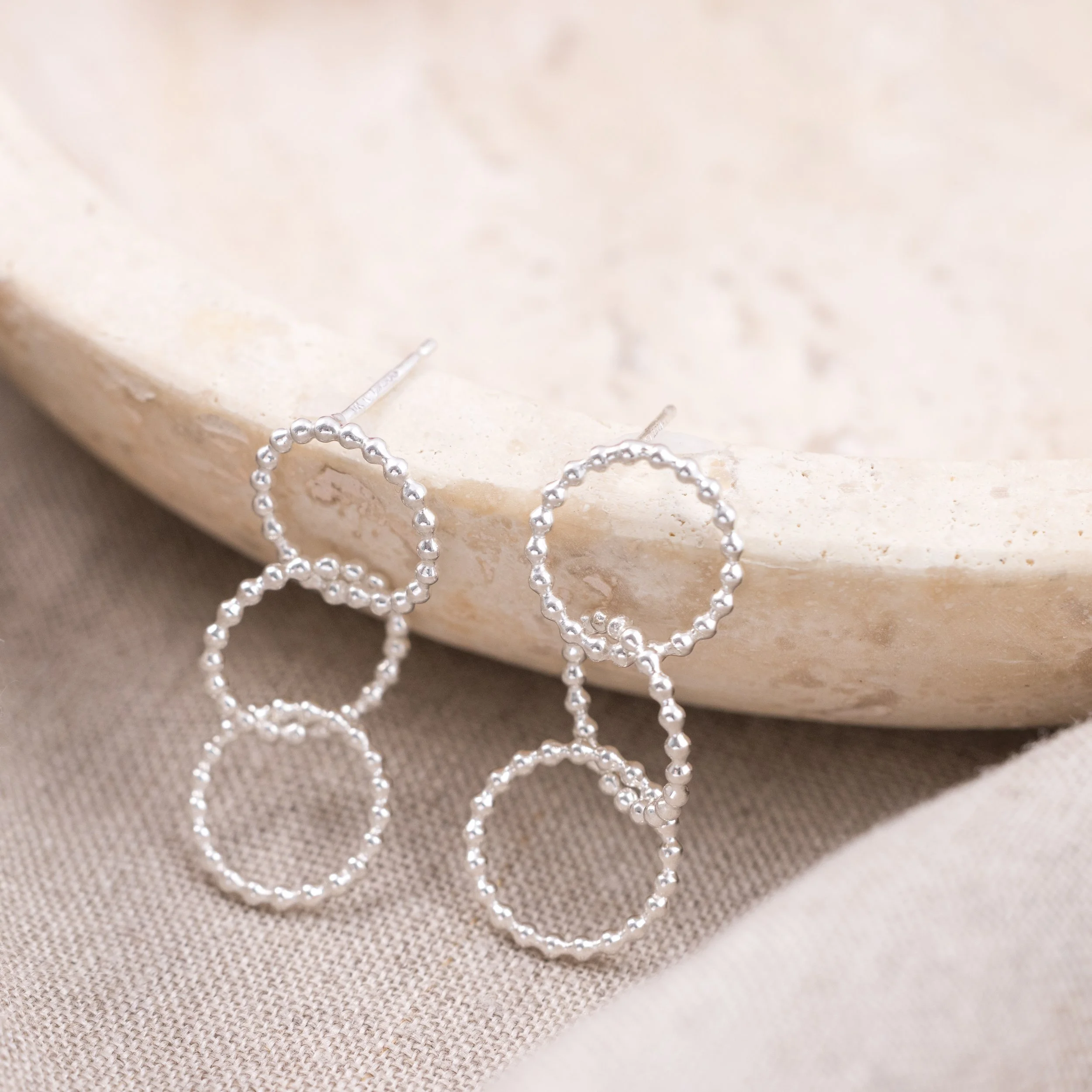Sterling silver multi-hoop earrings with polished bead accents and textured loops arranged in a layered, contemporary design.