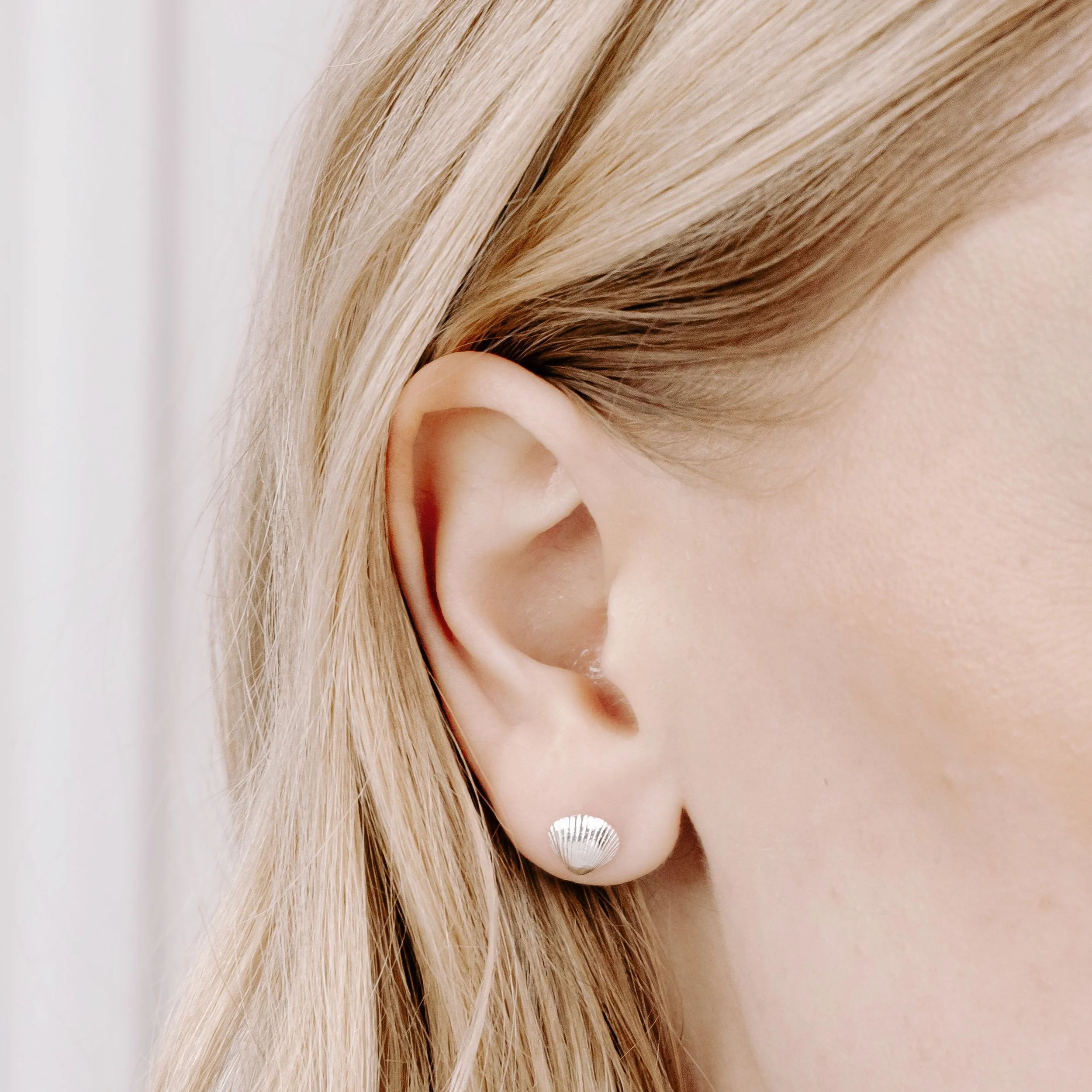 Sterling silver clamshell stud earrings with textured detailing, inspired by coastal seashells.