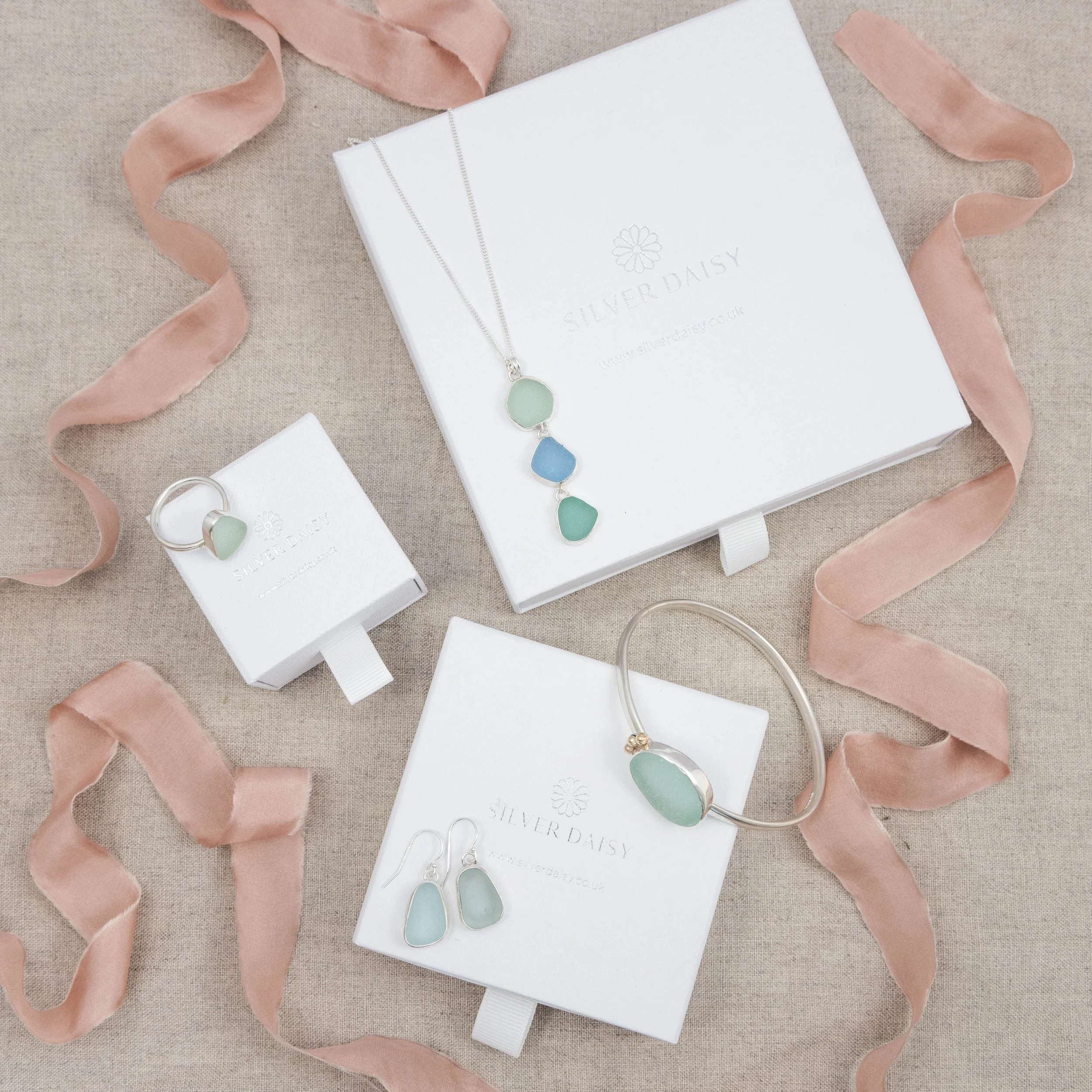 Sterling silver pendant necklace with cascading multi-coloured sea glass drops in green and blue tones, inspired by coastal style.