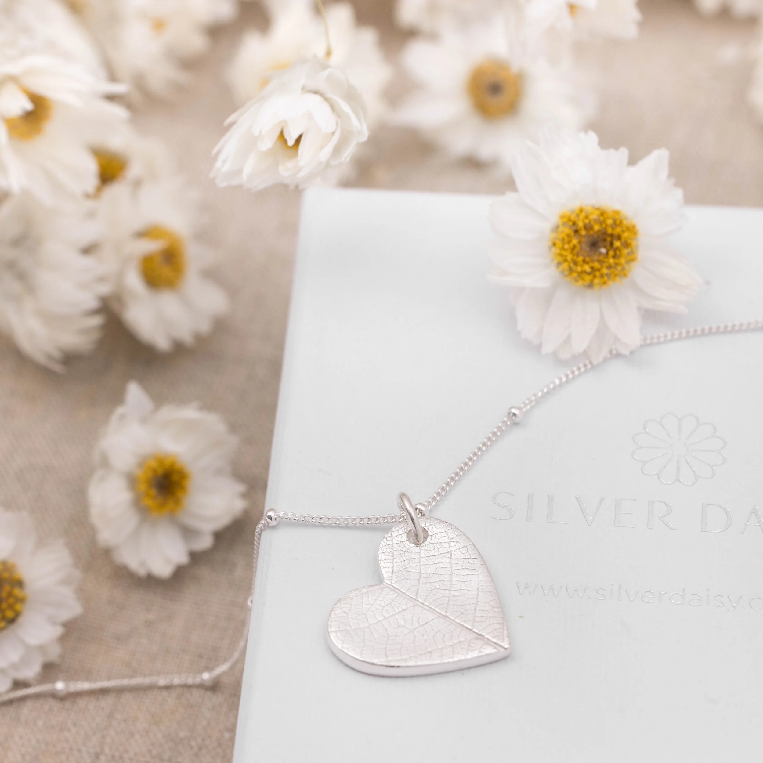 Sterling silver heart pendant with delicate leaf vein texture on a fine silver chain.
