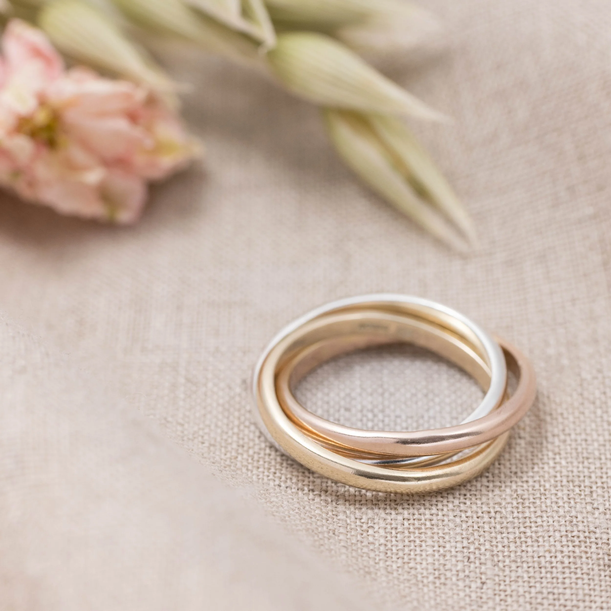 9ct gold & sterling silver trinity ring featuring interlocking silver, yellow and rose gold bands with a polished finish. Also known as a russian wedding ring.