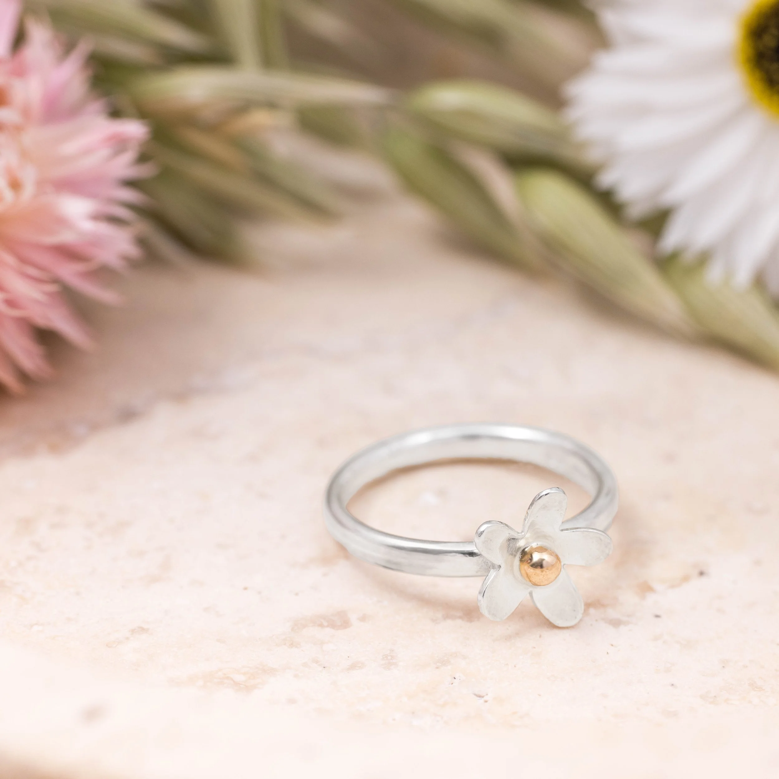 Sterling silver daisy ring with a polished band and detailed medium-sized flower design featuring 9ct gold stamen and a domed centre.