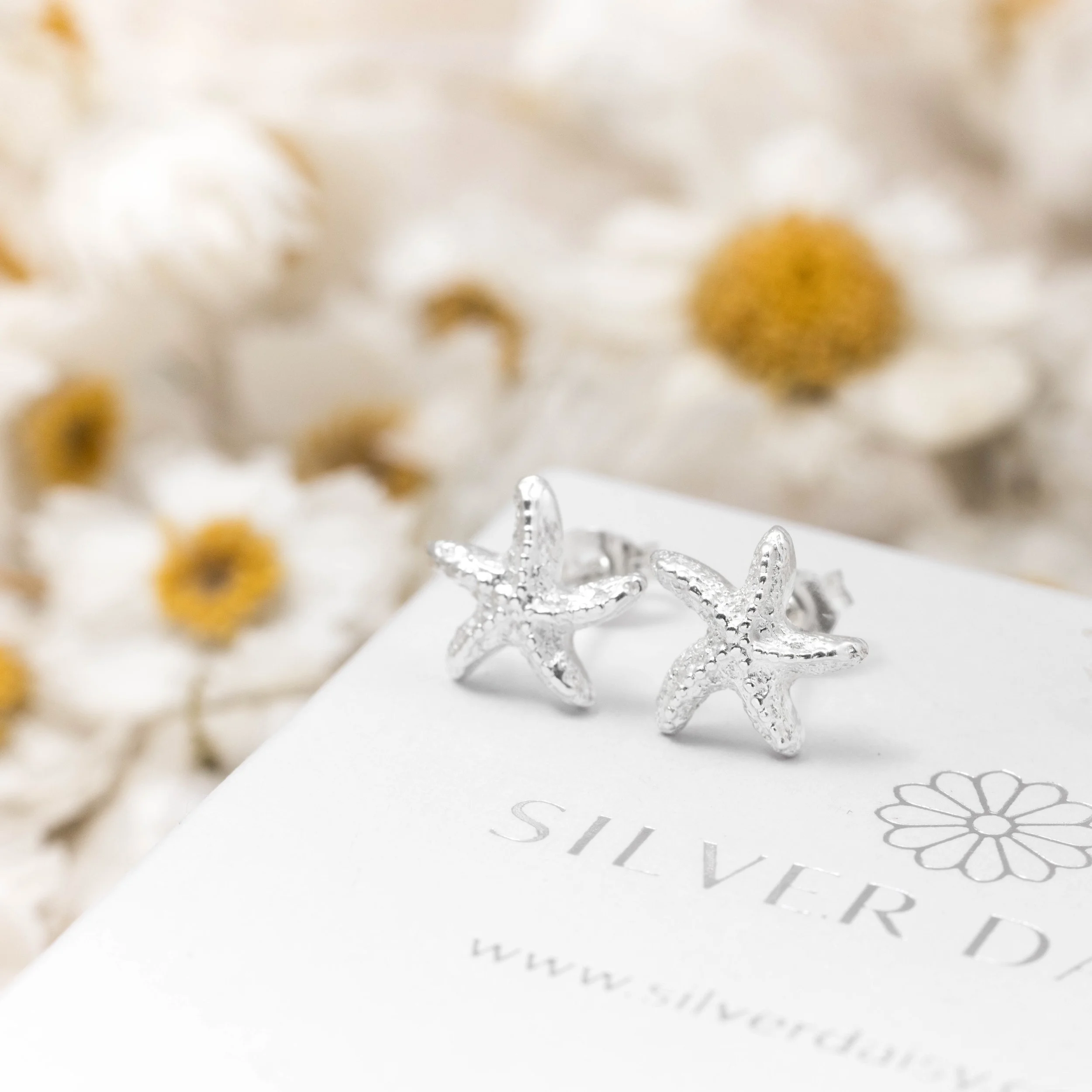 Silver starfish stud earrings with textured detailing and polished finish, part of the Silver Daisy Coastal Collection.