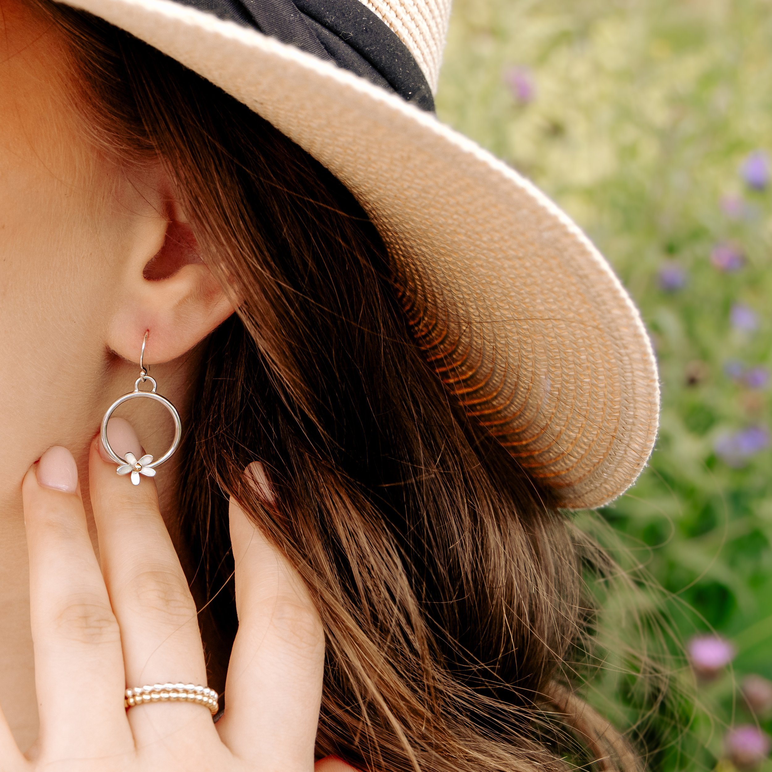 Sterling silver hoop earrings with delicate daisy flower charms, featuring 9ct gold stamen, and a polished and lightweight finish.