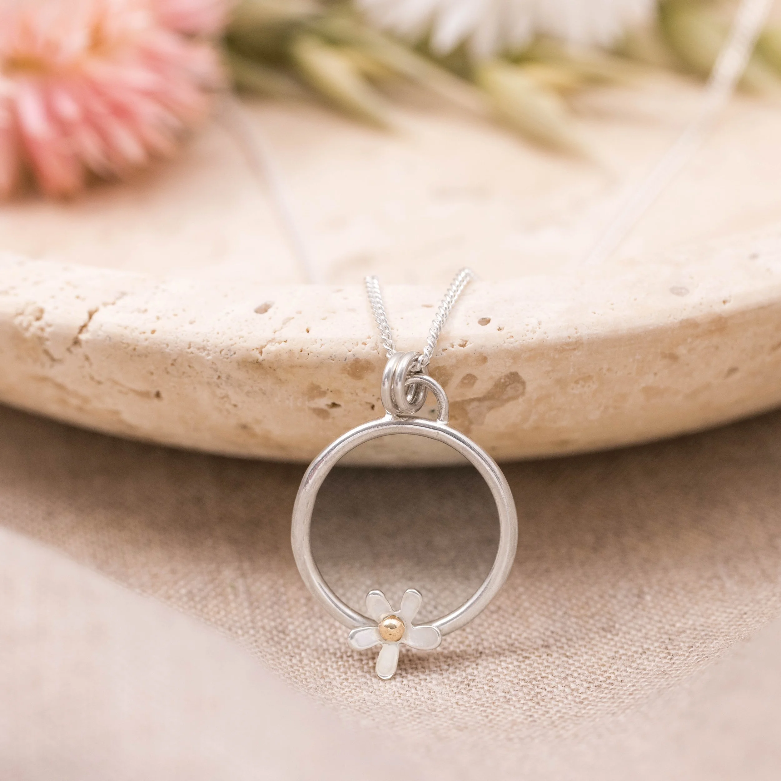 Sterling silver hoop pendant necklace with an open daisy flower design featuring a 9ct gold stamen on a fine chain, polished finish, minimalist floral jewellery.