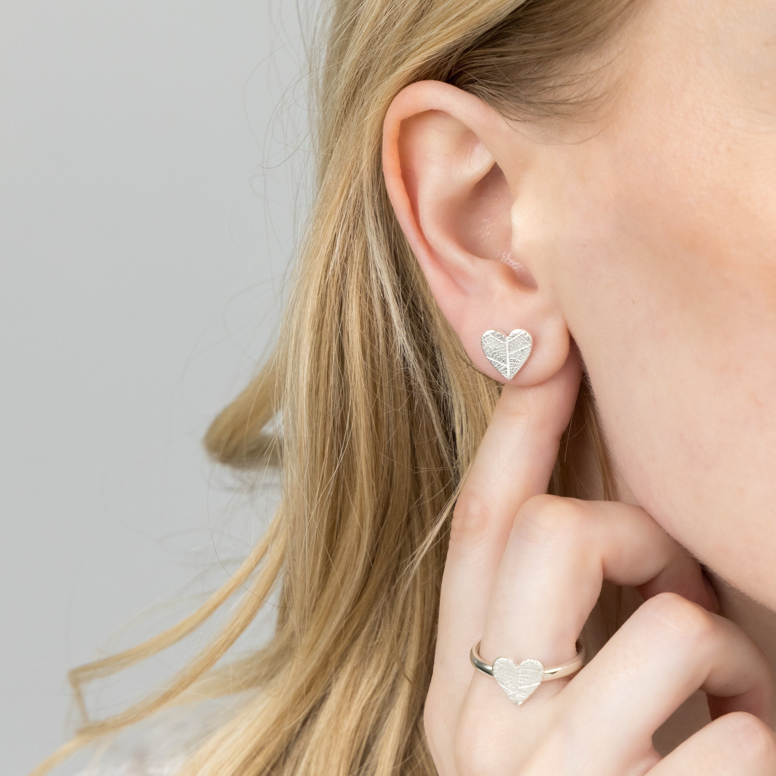Sterling silver heart stud earrings with delicate imprinted leaf texture on a polished finish.