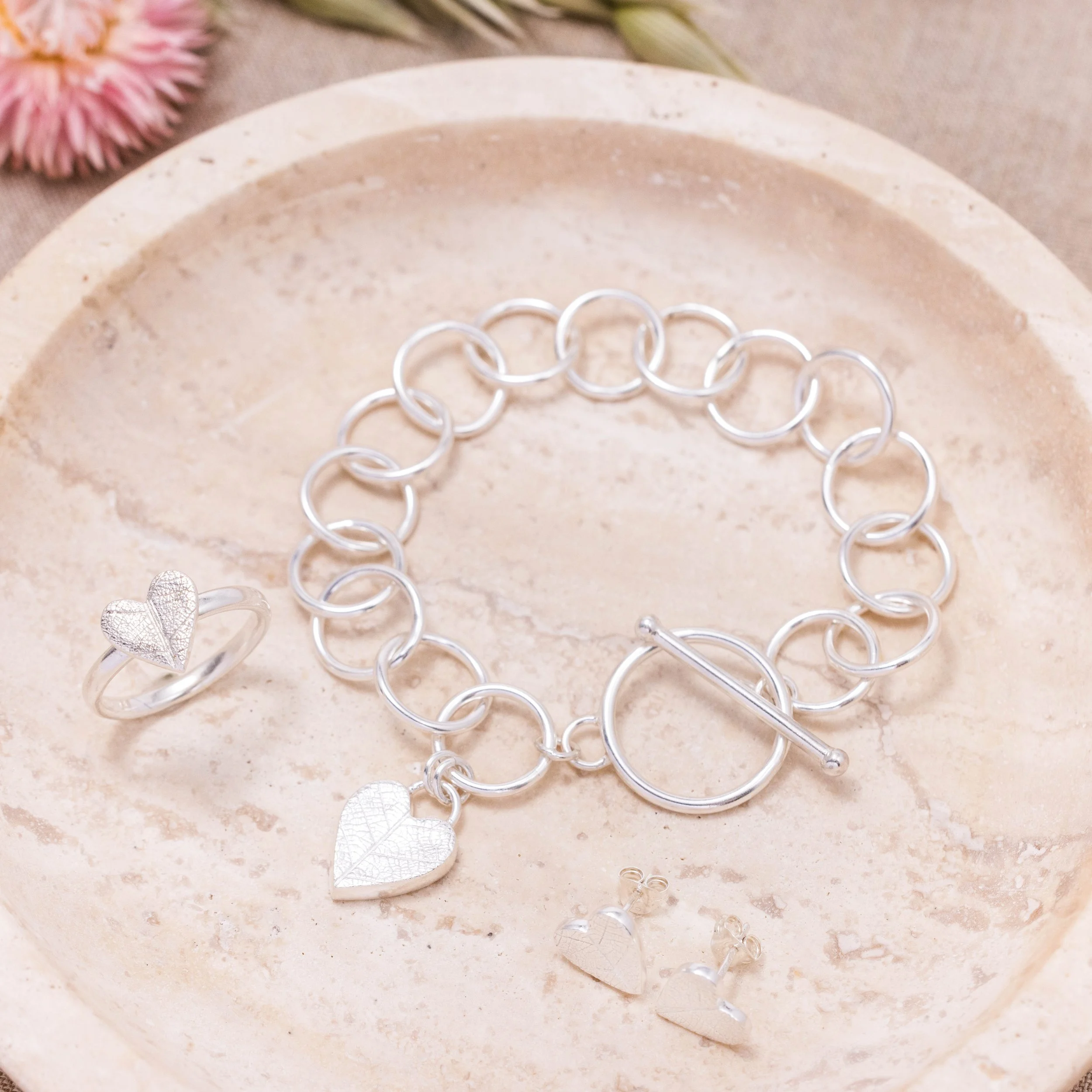 Sterling silver heart-shaped ring with delicate pressed leaf pattern on a polished band.