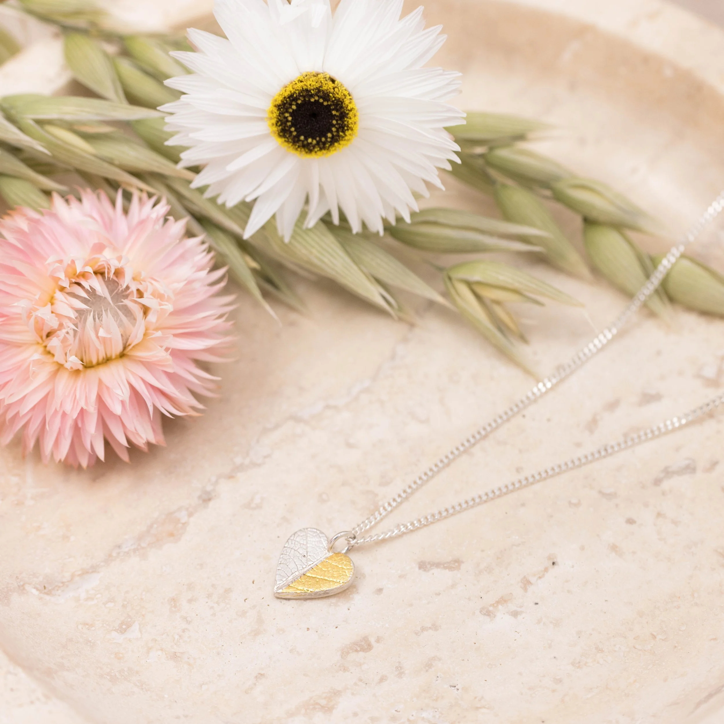 Gold and silver heart leaf pendant necklace with textured leaf pattern on a fine silver chain, handmade botanical jewellery.