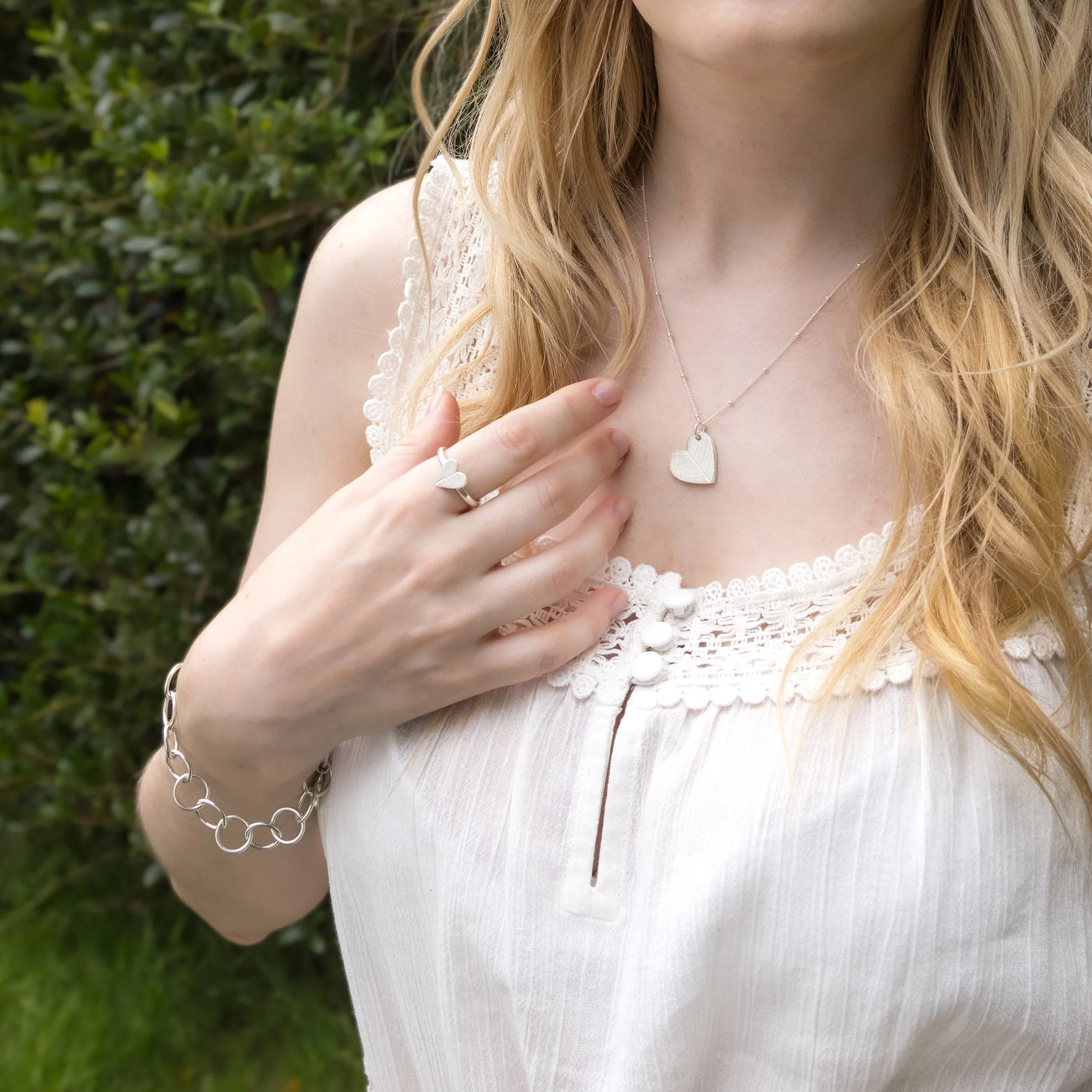 Sterling silver heart-shaped ring with delicate pressed leaf pattern on a polished band.