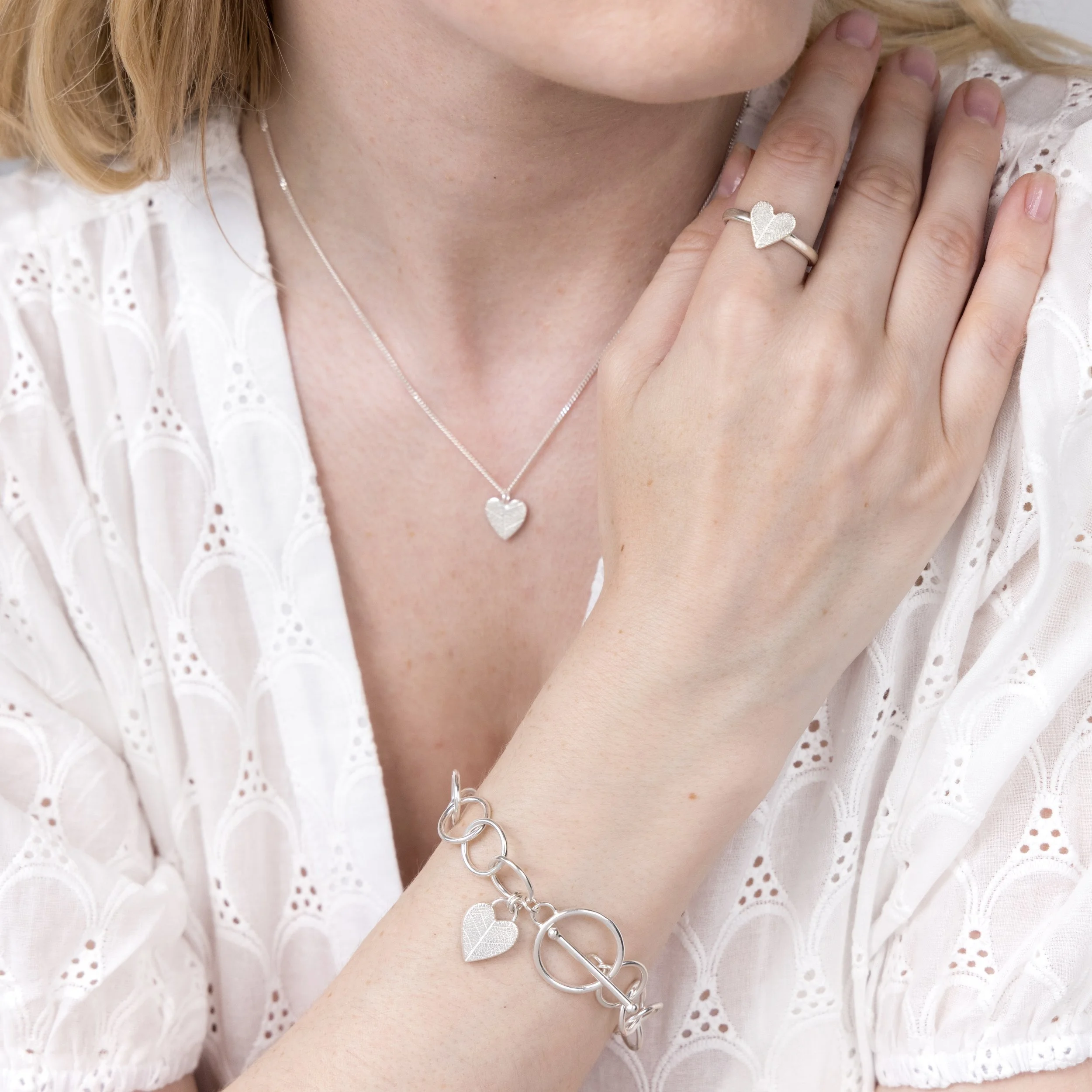 Sterling silver heart-shaped ring with delicate pressed leaf pattern on a polished band.