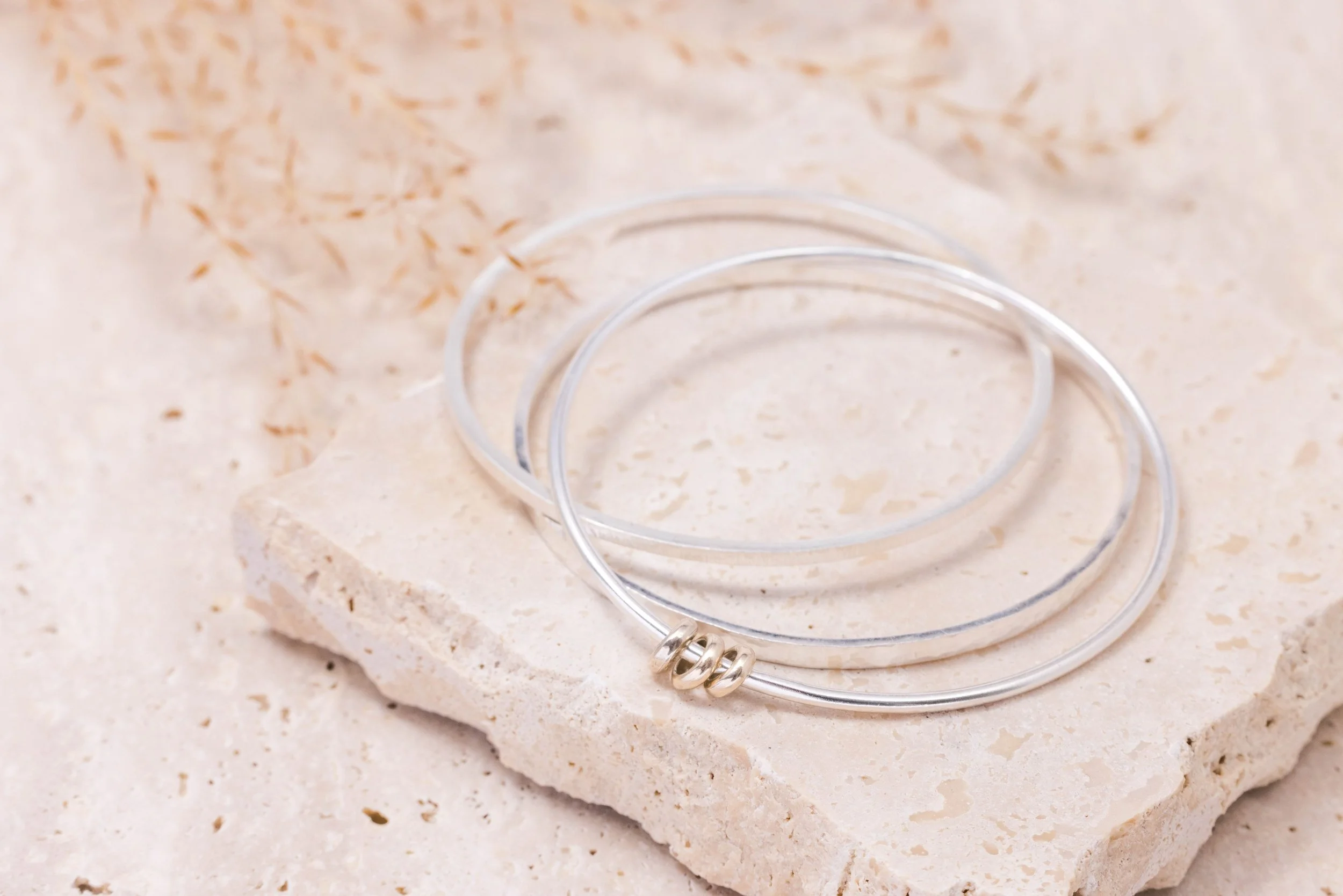 Slim sterling silver stacking bangle with a hammered line texture, polished finish, and minimalist contemporary design.