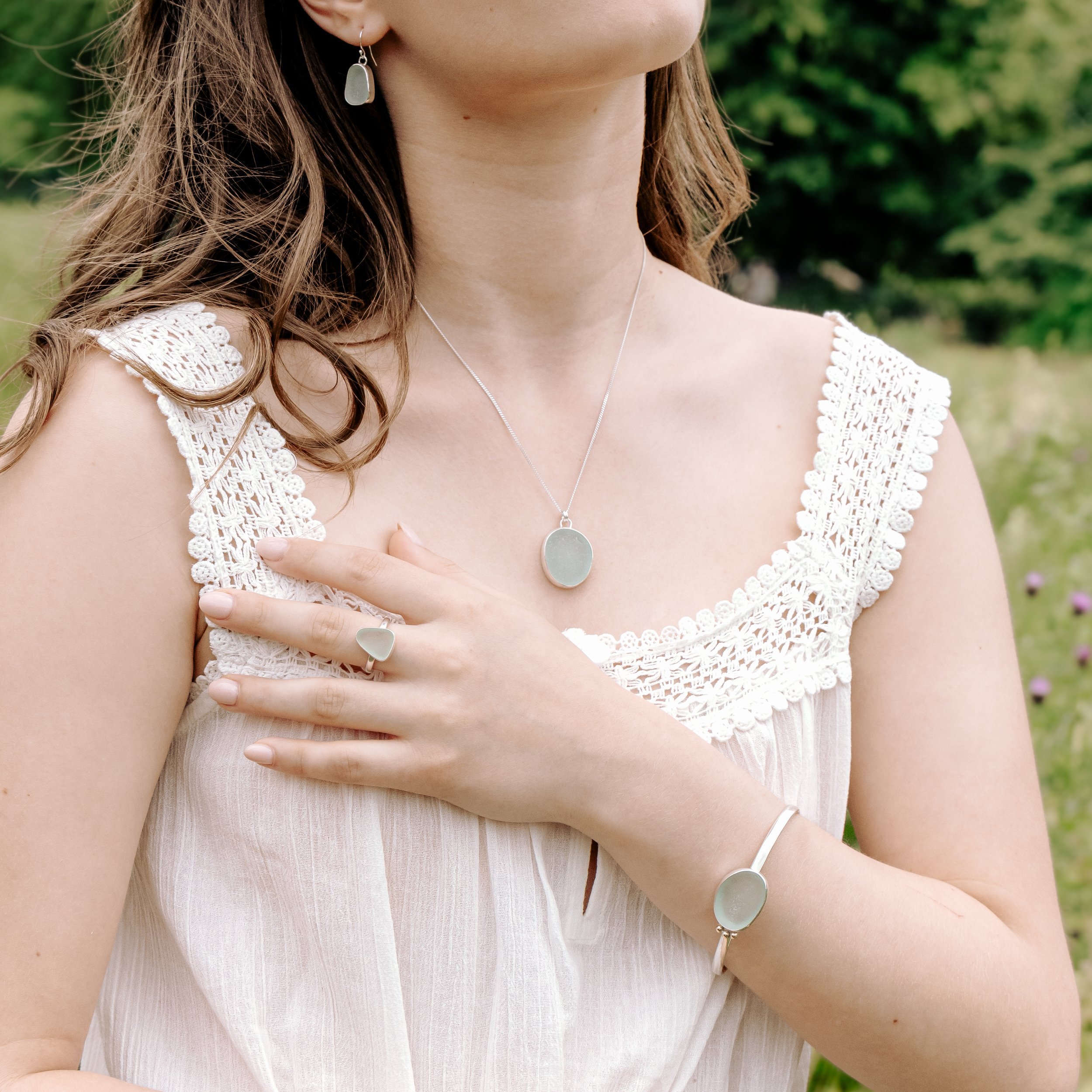 Aqua sea glass pebble set in polished silver on a delicate chain, coastal-inspired handmade necklace.