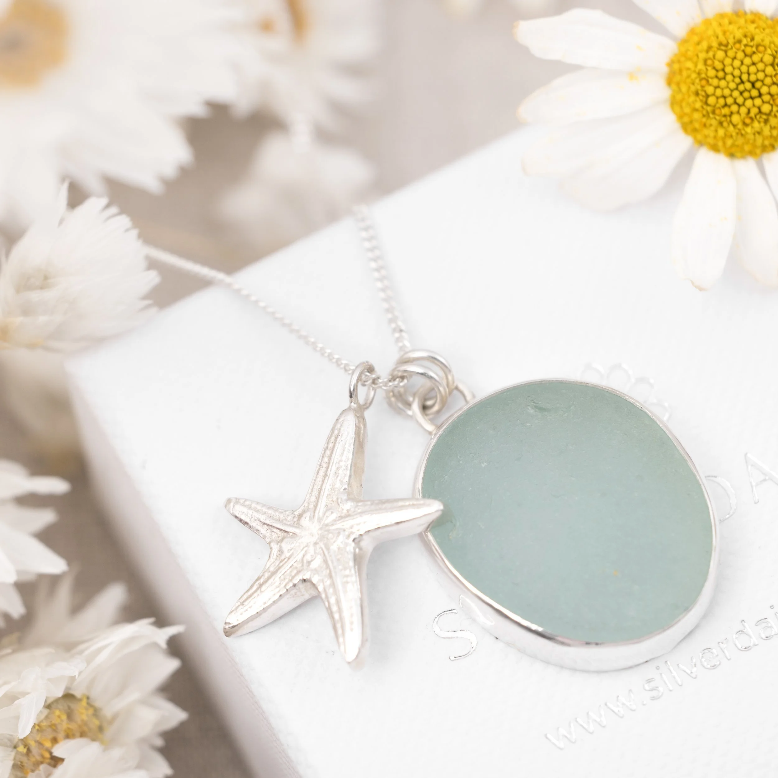 Aquamarine sea glass pebble and sterling silver starfish pendant cluster on a fine silver chain. Coastal inspired jewellery by Silver Daisy.
