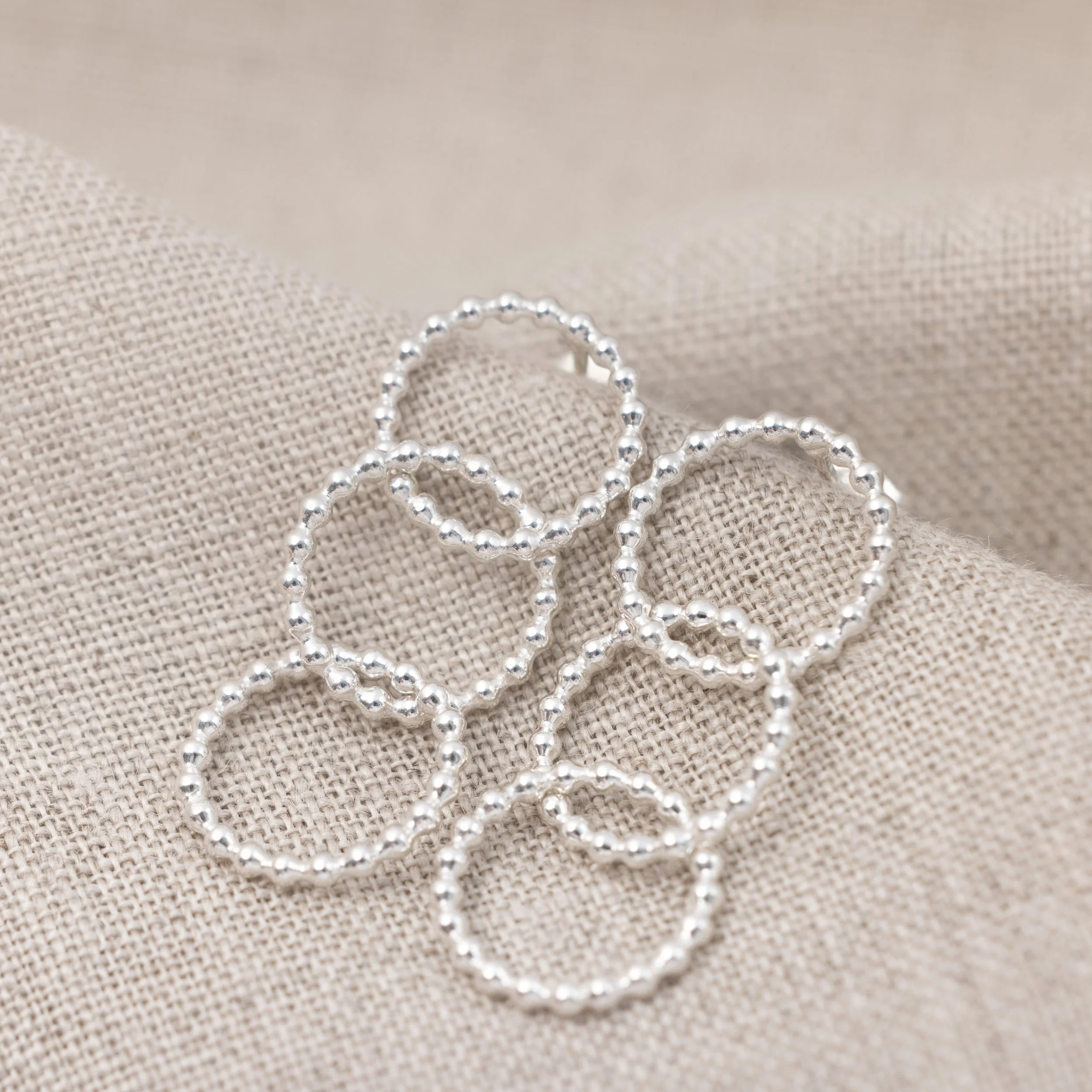 Sterling silver multi-hoop earrings with polished bead accents and textured loops arranged in a layered, contemporary design.