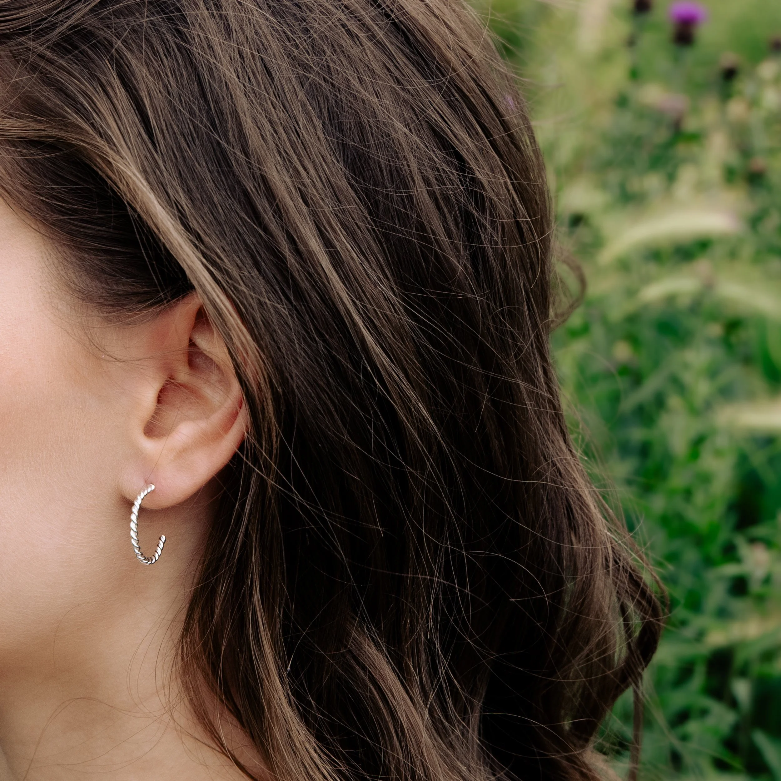Polished sterling silver twist hoop earrings with a textured spiral design, lightweight and elegant for everyday wear.