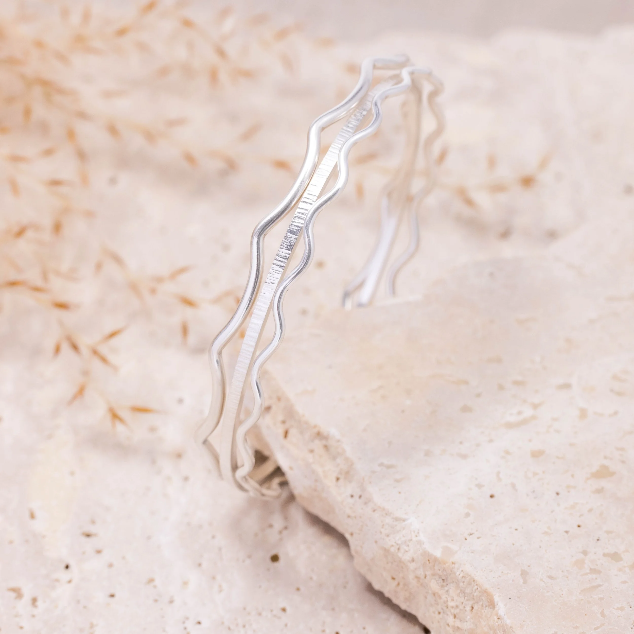 Slim sterling silver stacking bangle with a hammered line texture, polished finish, and minimalist contemporary design.