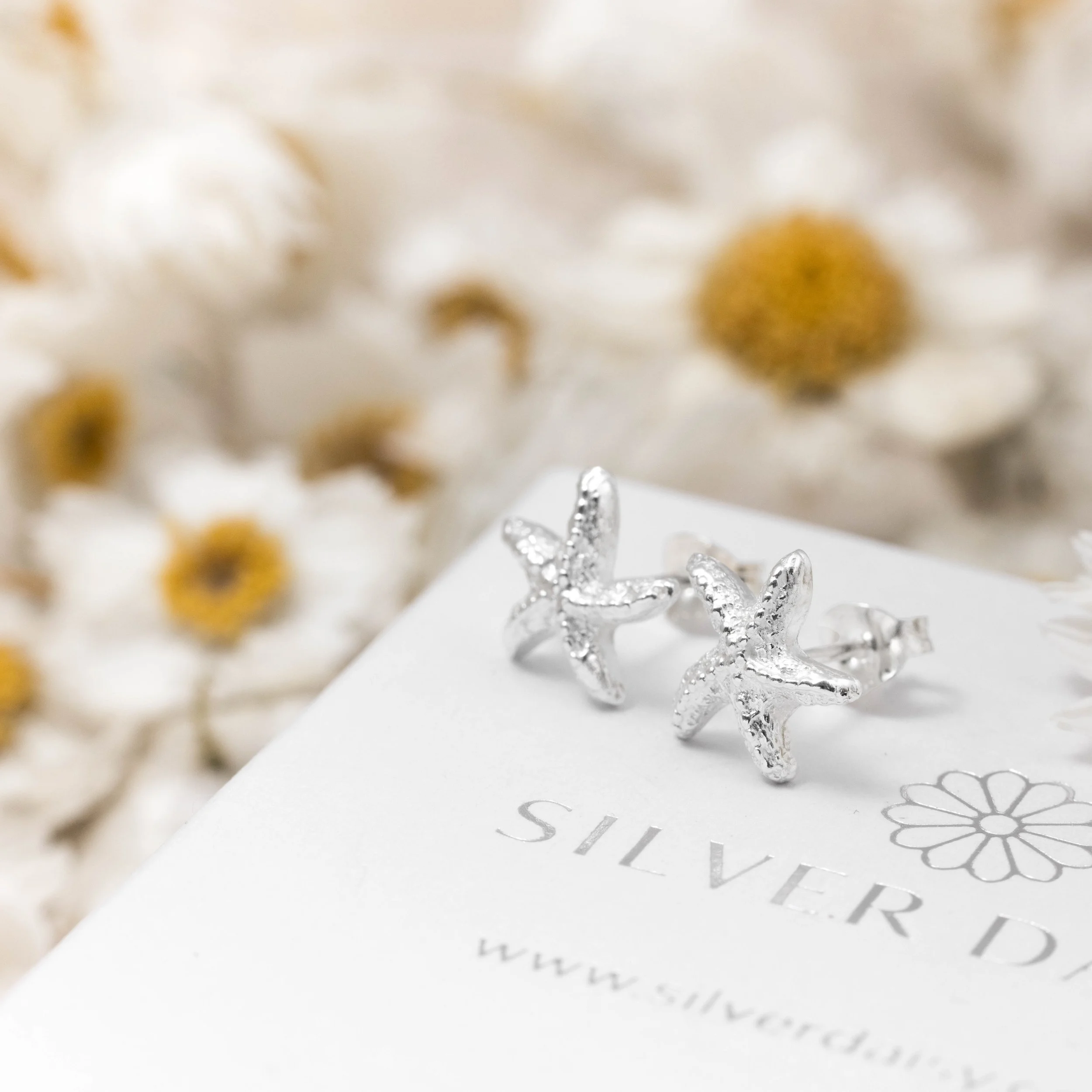 Silver starfish stud earrings with textured detailing and polished finish, part of the Silver Daisy Coastal Collection.