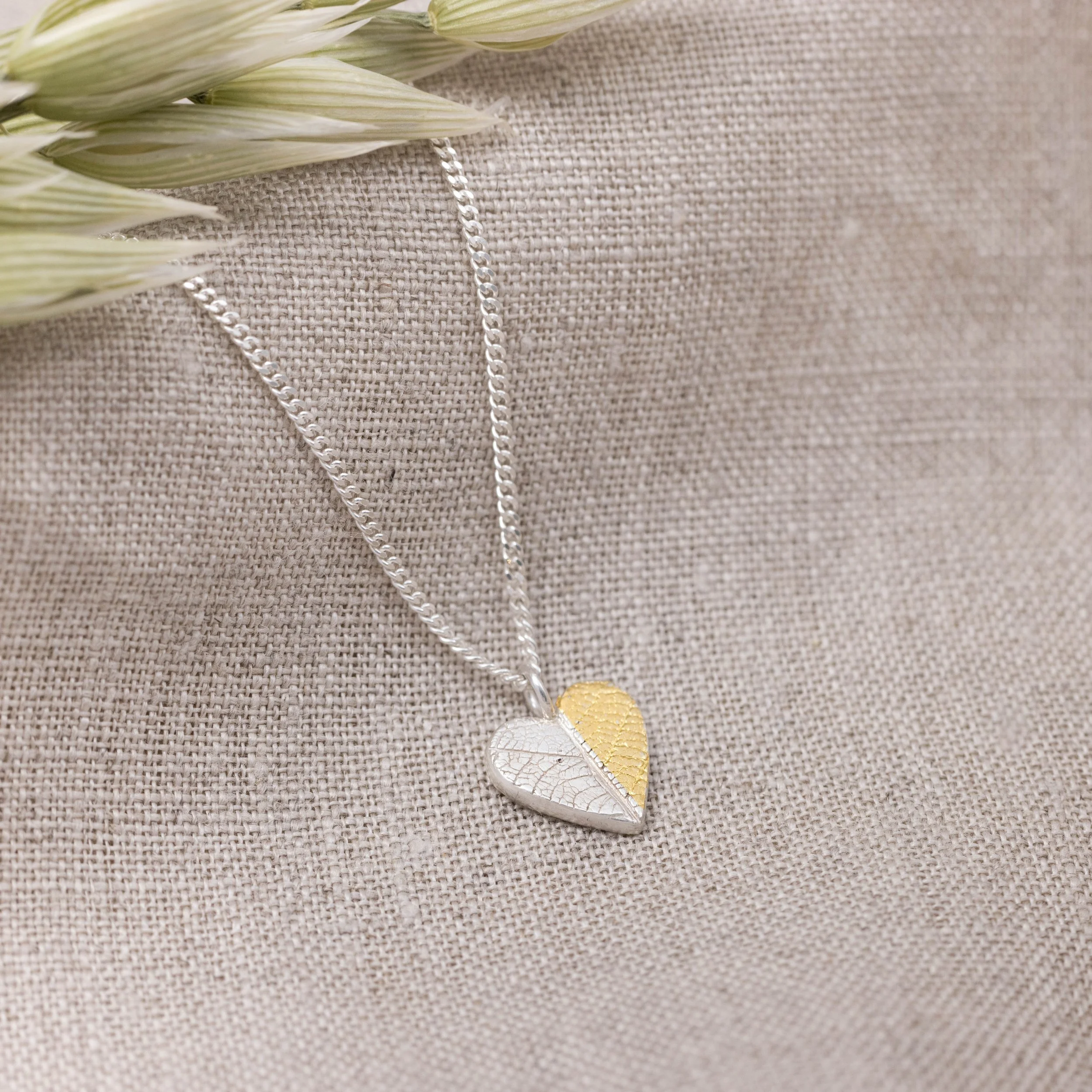 Gold and silver heart leaf pendant necklace with textured leaf pattern on a fine silver chain, handmade botanical jewellery.