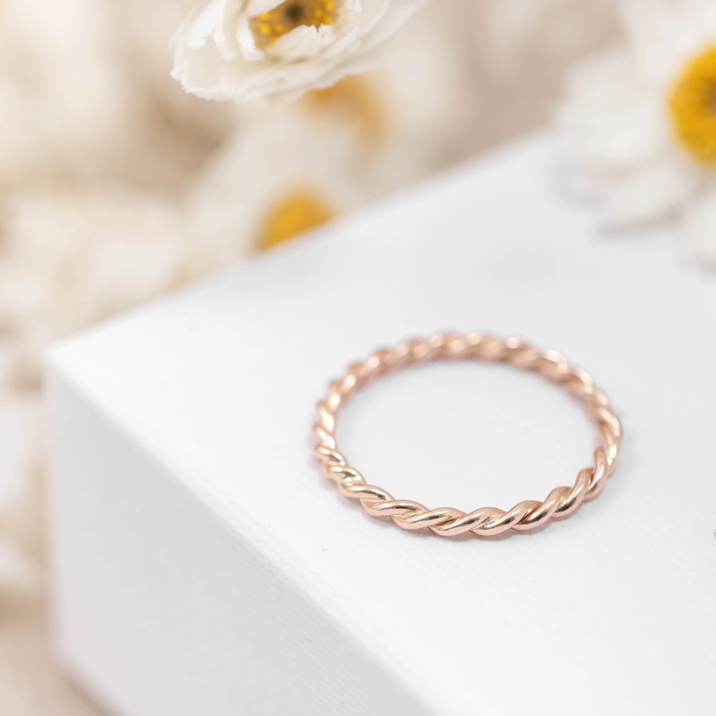 Delicate 9ct rose gold stacking ring with a twisted rope design, polished finish, ideal for layering or wearing as a minimalist band.