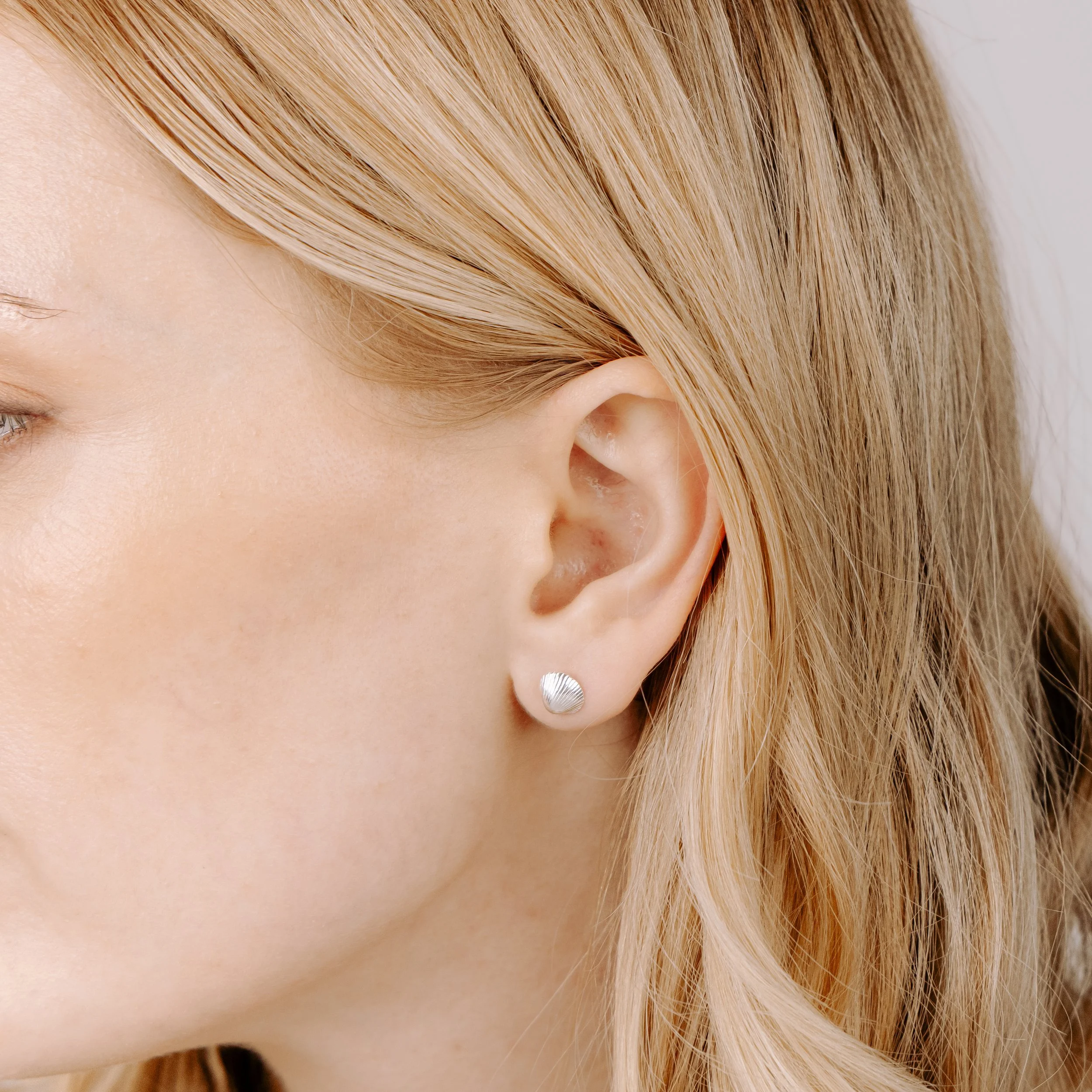 Sterling silver clamshell stud earrings with textured detailing, inspired by coastal seashells.