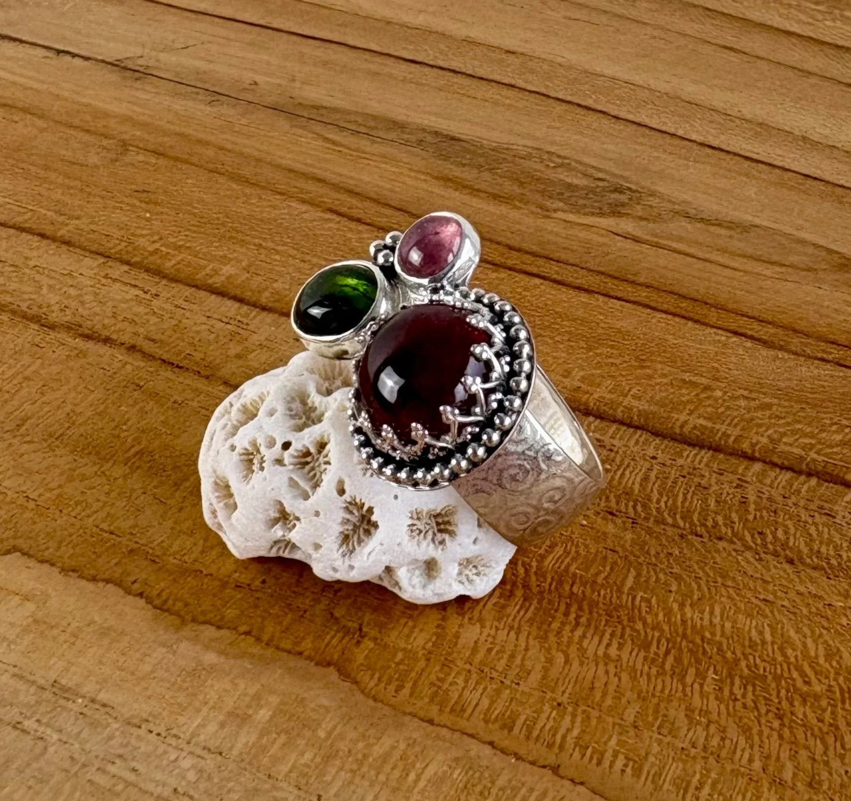 190 euro. 3 Toermalijnen in rood, groen en roze. Gewalst krulpatroon op de iets bolle ringband. Maat 18 1/4. Zilver (details geoxideerd) en fijnzilver.