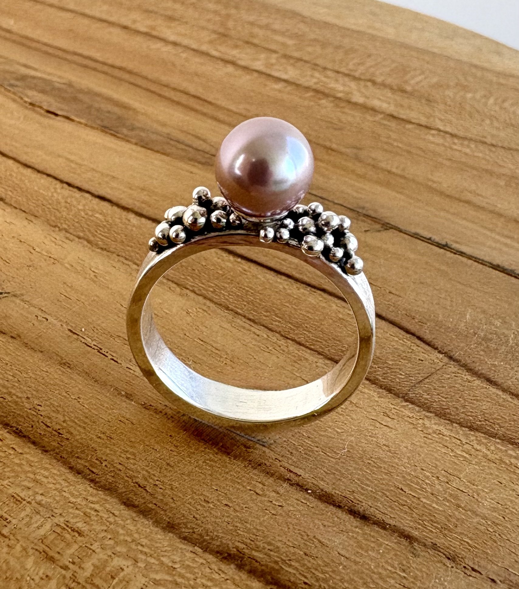 175 euro. Zoetwater Parel A++, licht roze/blauw van kleur. Ringband met matte finish en kleine granules. Maat 17 3/4. Zilver en fijnzilver.