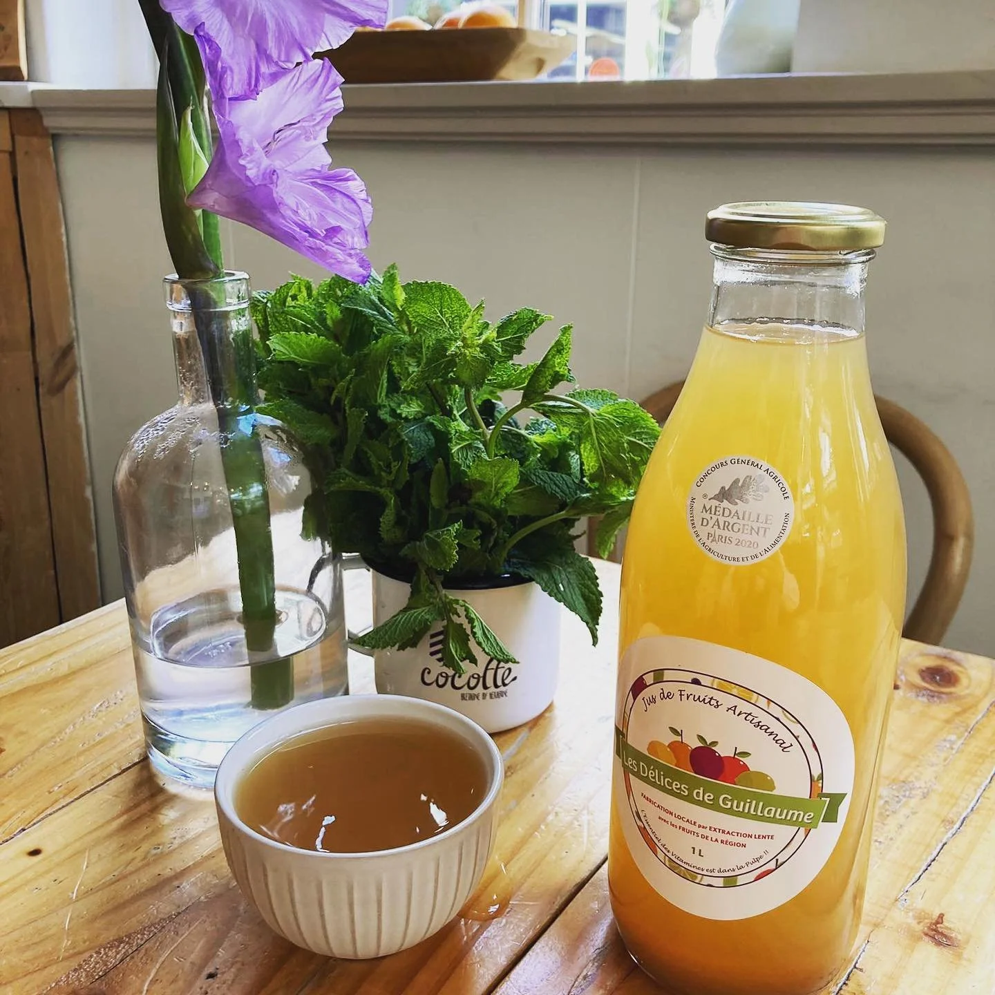 A wooden table with a bottle of family homemade apple juice. The best you can find from far away !