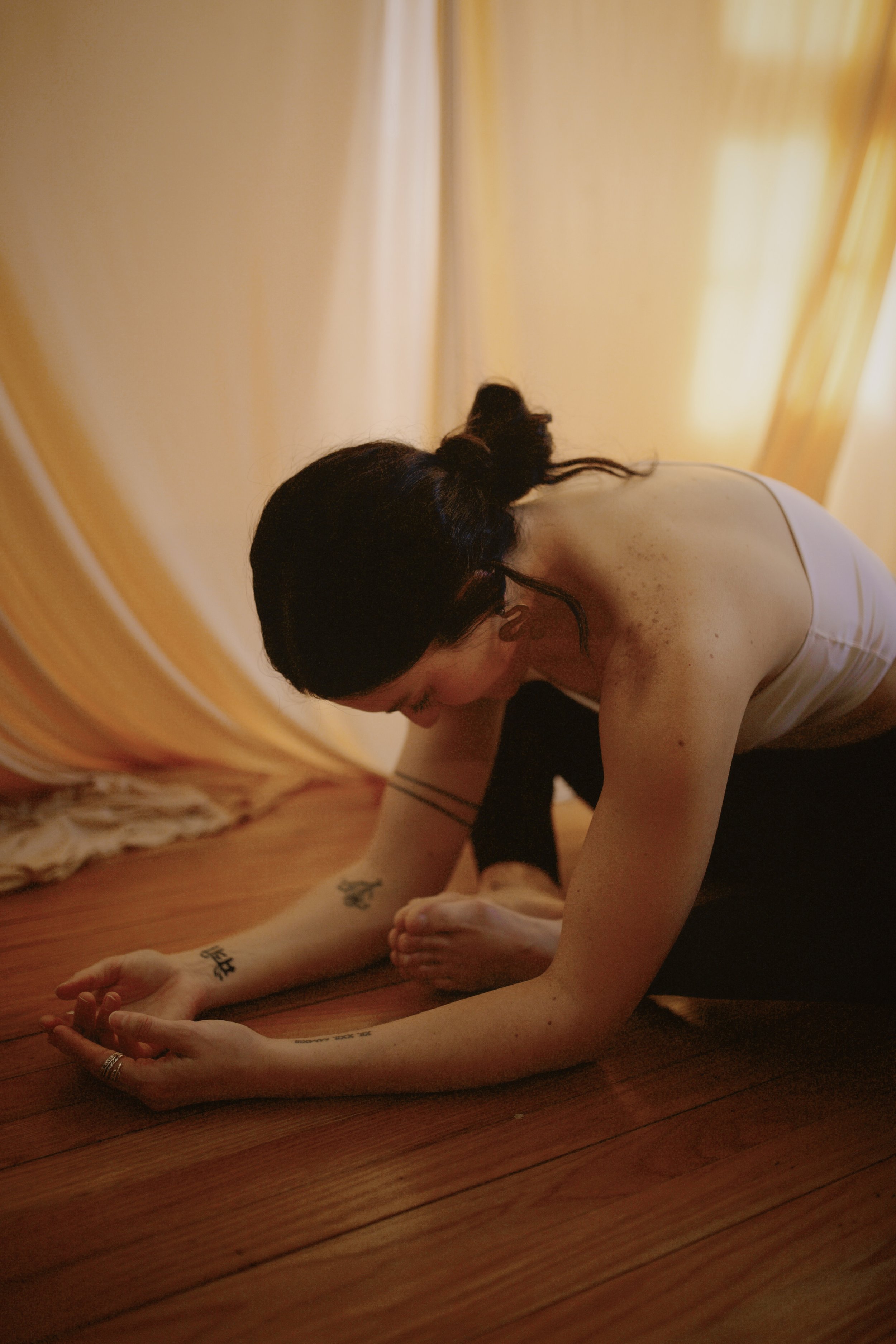 Woman practicing yoga on a mat, sitting cross-legged with hands in a prayer position at her chest.