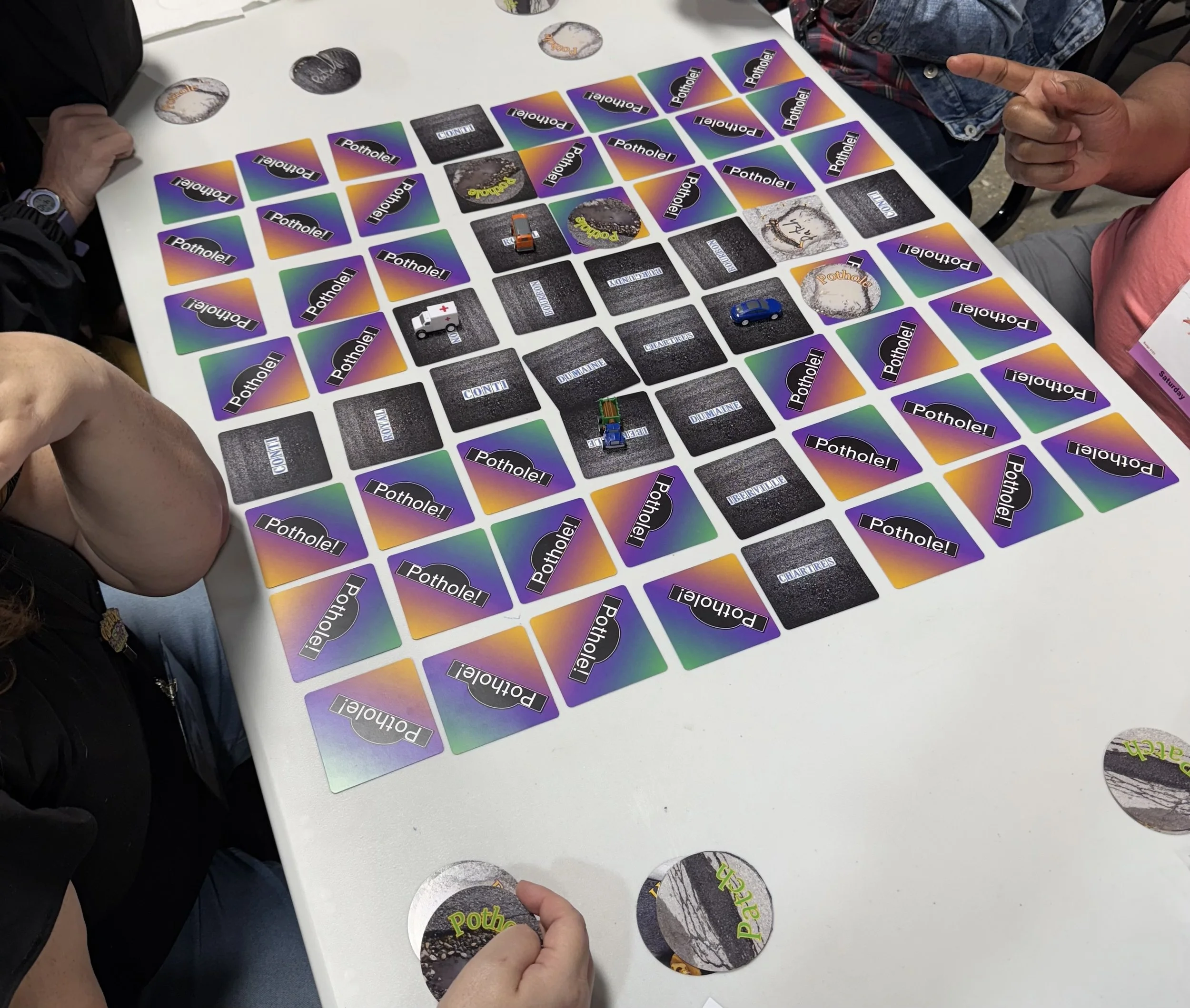 A card game that uses a grid of cards on a white table.