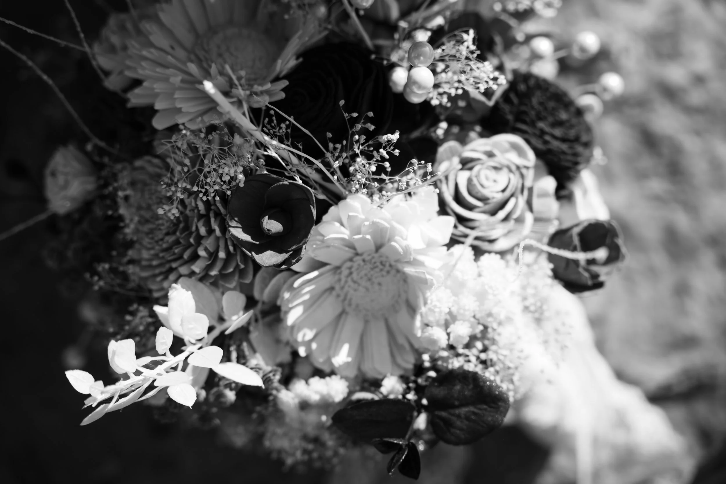 Black and white photo of a bouquet of various flowers, including roses, daisies, and small berries.