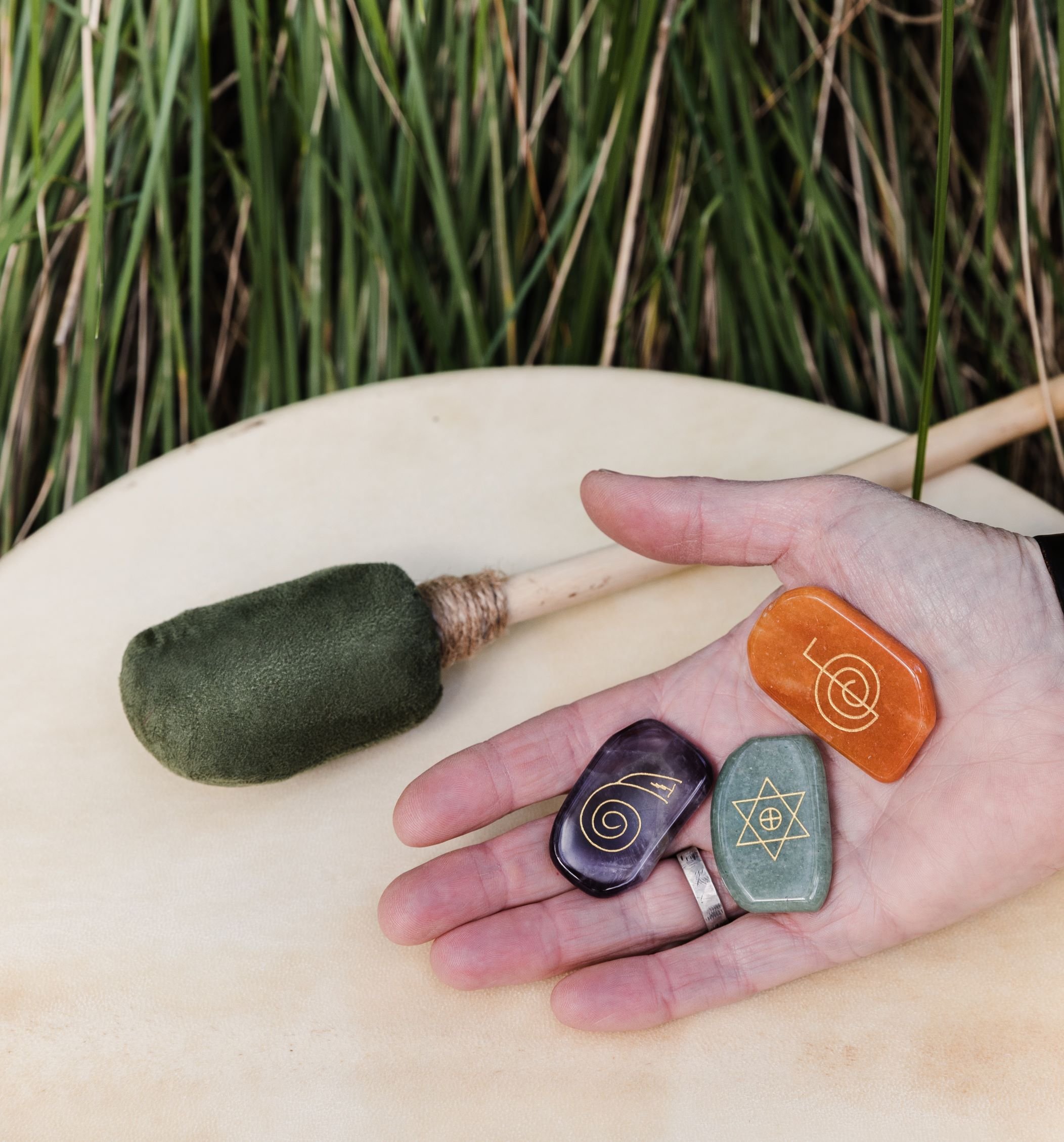Reiki healing tools including crystals and drum held in hand, representing energetic healing sessions in Beechworth.