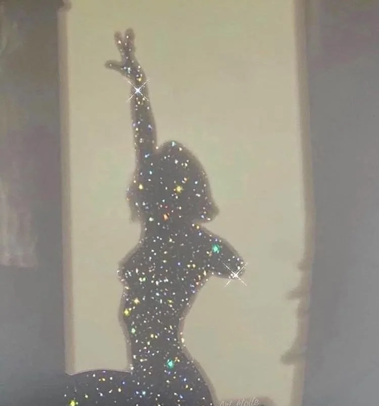 Silhouette of a woman with short hair, striking a dance pose with one arm raised and the other bent at the elbow, her hand near her head, outlined in sparkling, glittering stars and multicolored lights.