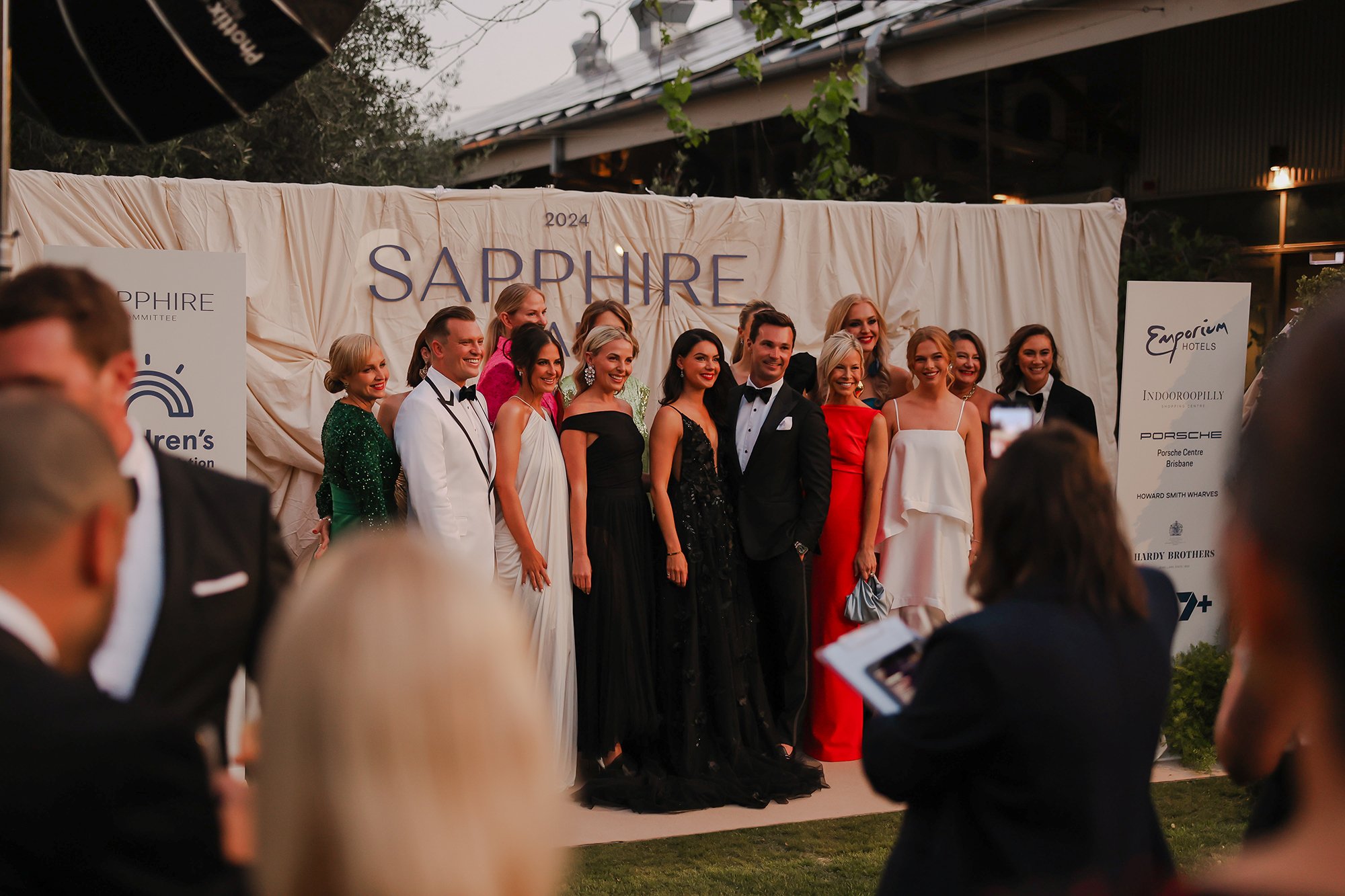 Group of people dressed in formal attire posing for a photo on a red carpet at the 2024 Sapphire event.