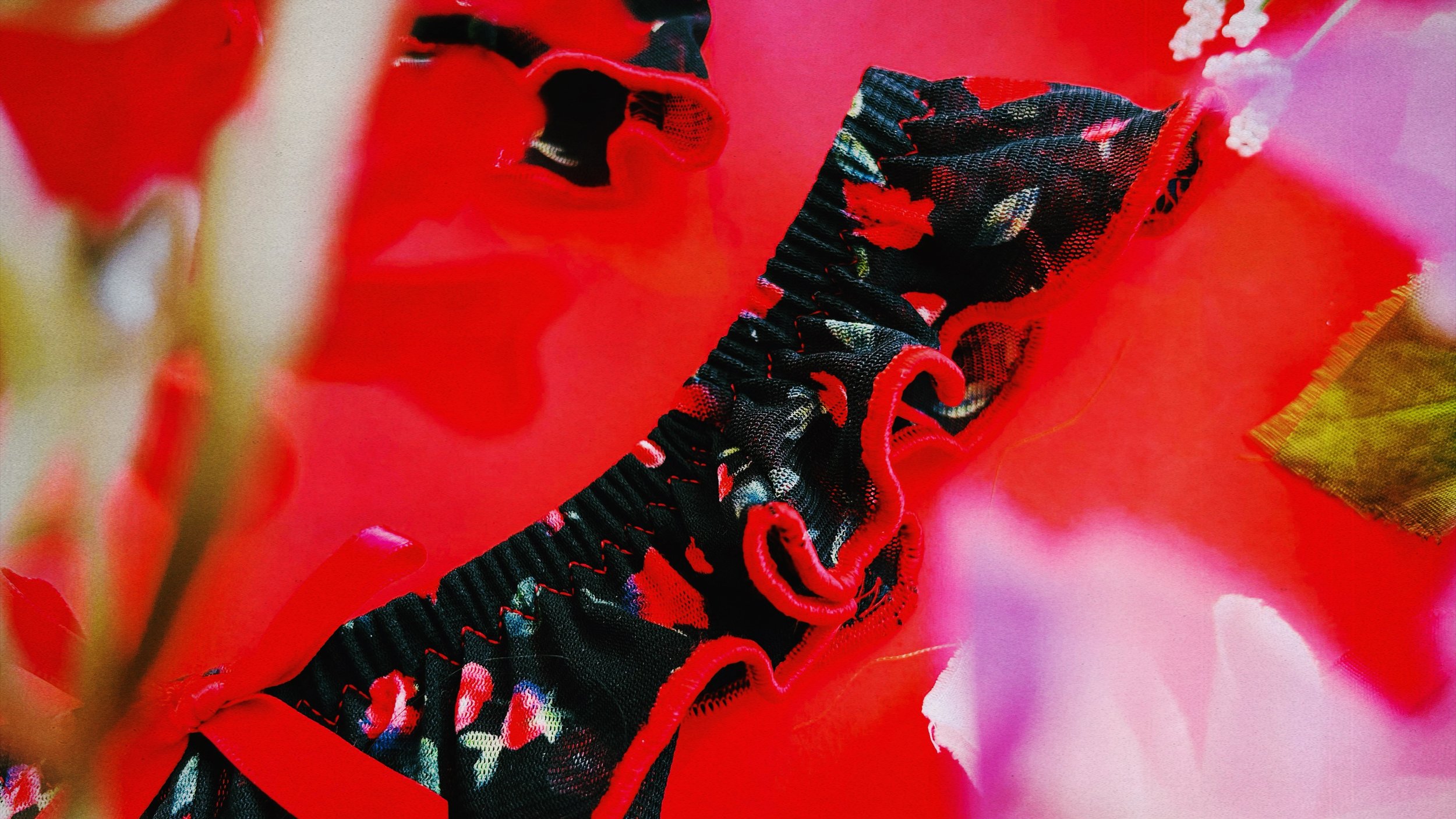 A detailed shot showcasing the intricate ruffles and cherry blossom floral print of the lingerie, accented with bold red hues.