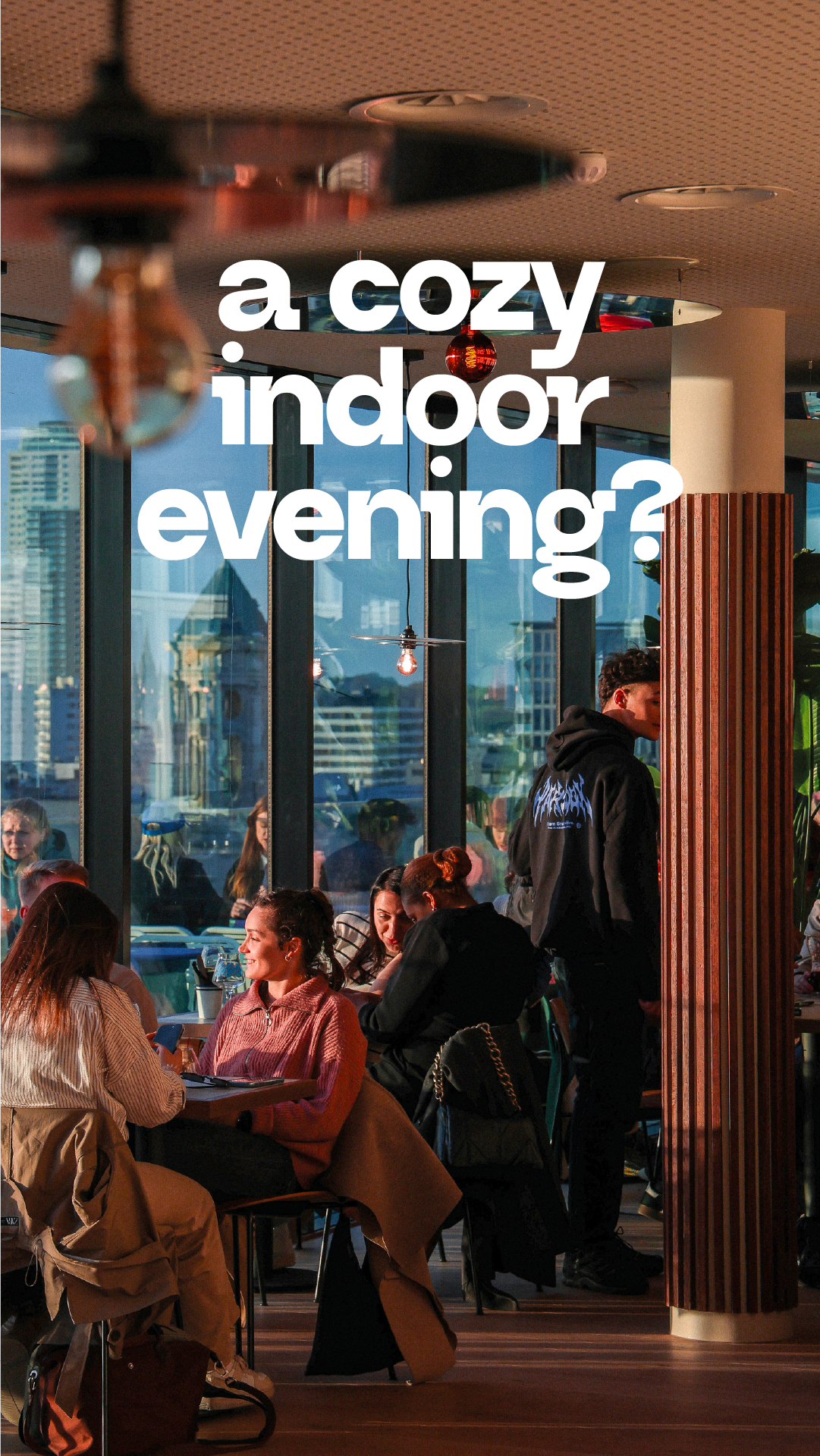 Un intérieur convivial avec des personnes assises autour de tables, profitant d'une soirée d'automne à l'intérieur d'un restaurant ou d'un café, avec de grandes fenêtres laissant passer la lumière naturelle et offrant une vue urbaine.